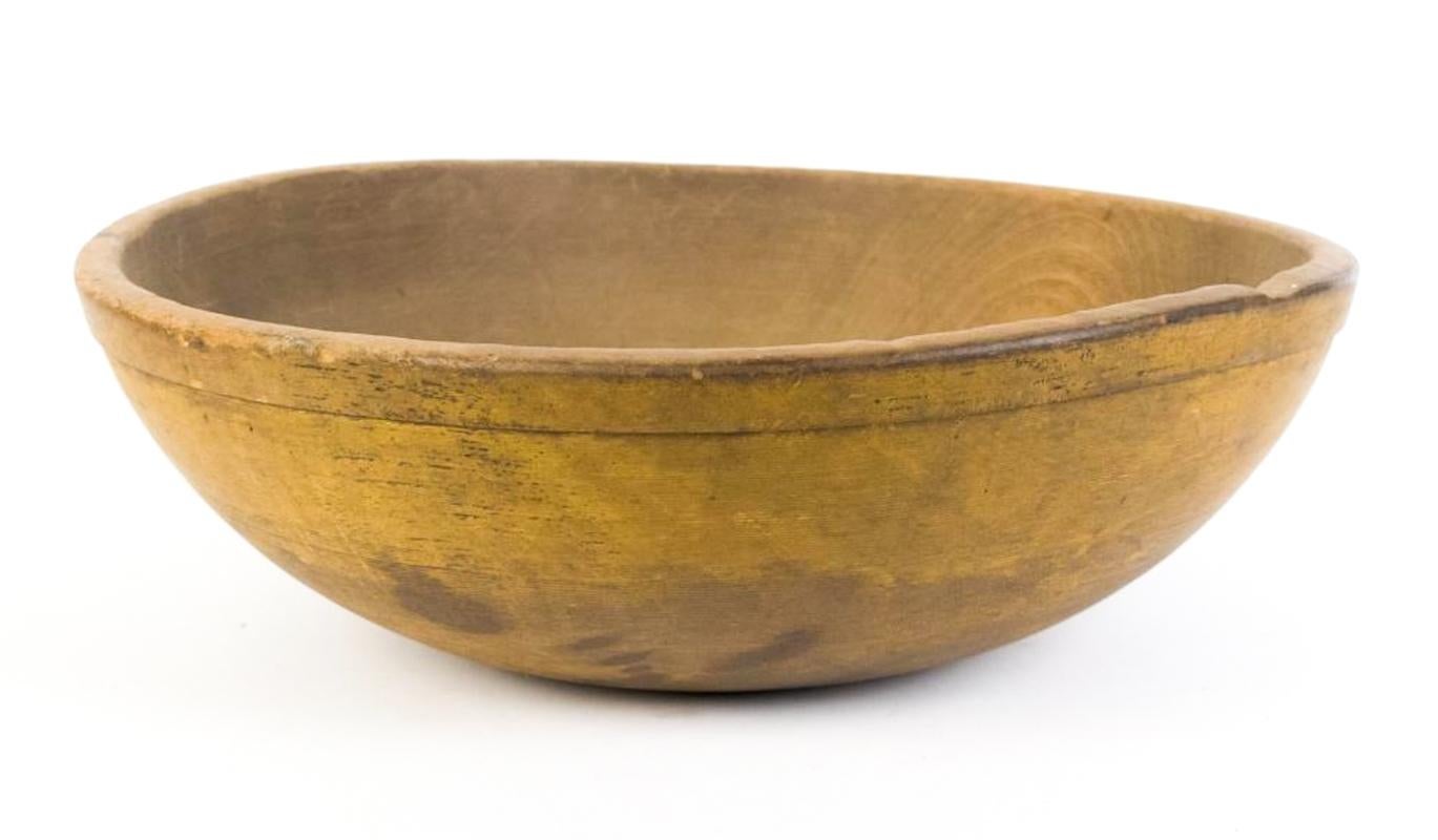 A beautifully timeworn 19th-century hand-turned wooden chopping bowl in its original mustard paint. The surface has aged to a rich, mellow ochre with deep, natural patina and heavy wear consistent with generations of use. Slightly out of round, as