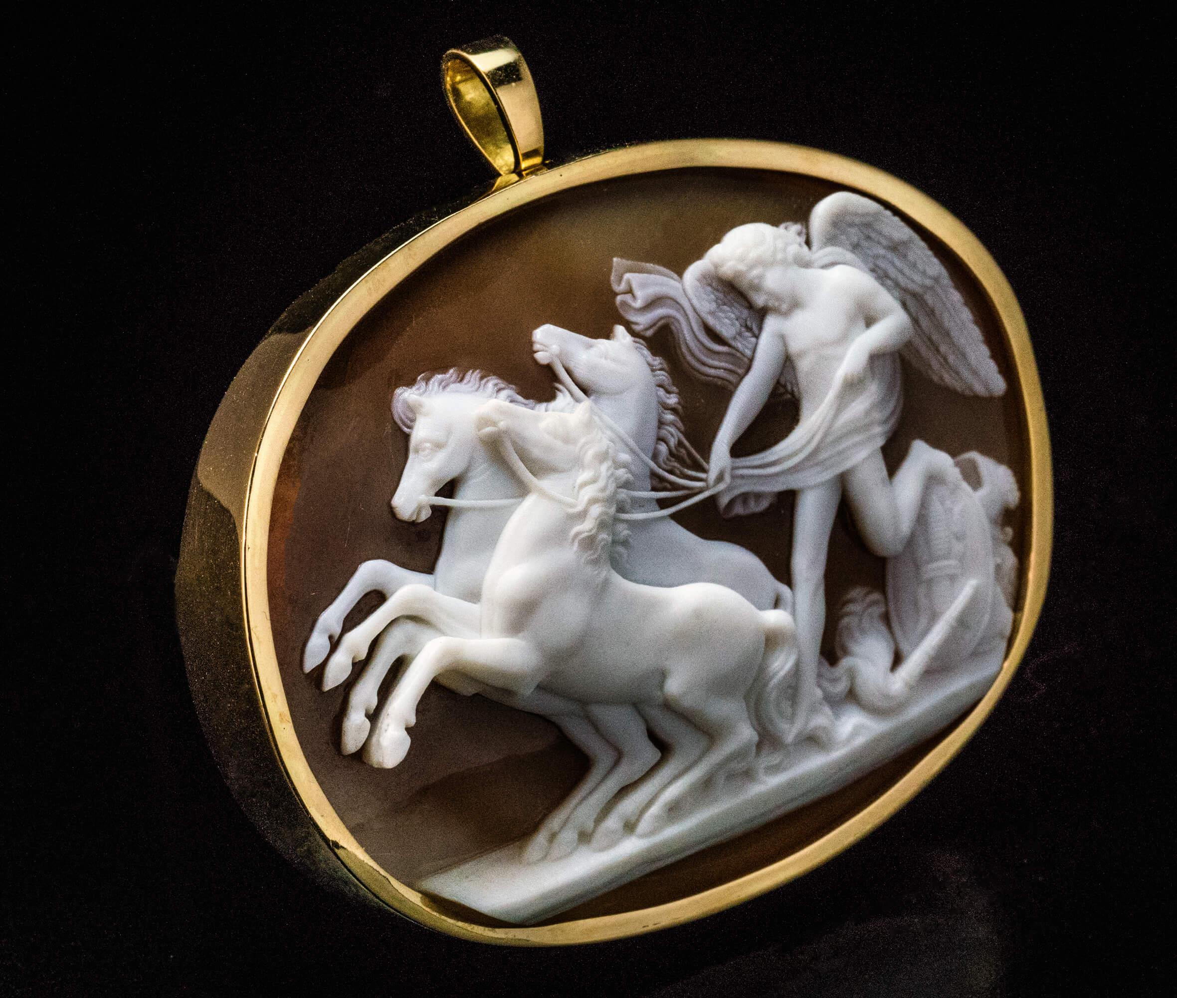 Italian, circa 1860s.

This large antique shell cameo is superbly carved after either Tommaso or Luigi Saulini with Peace (depicted as a winged youth) Halting the Horses of Mars. The cameo is set in an 18K gold bezel with a folding bail and a pin