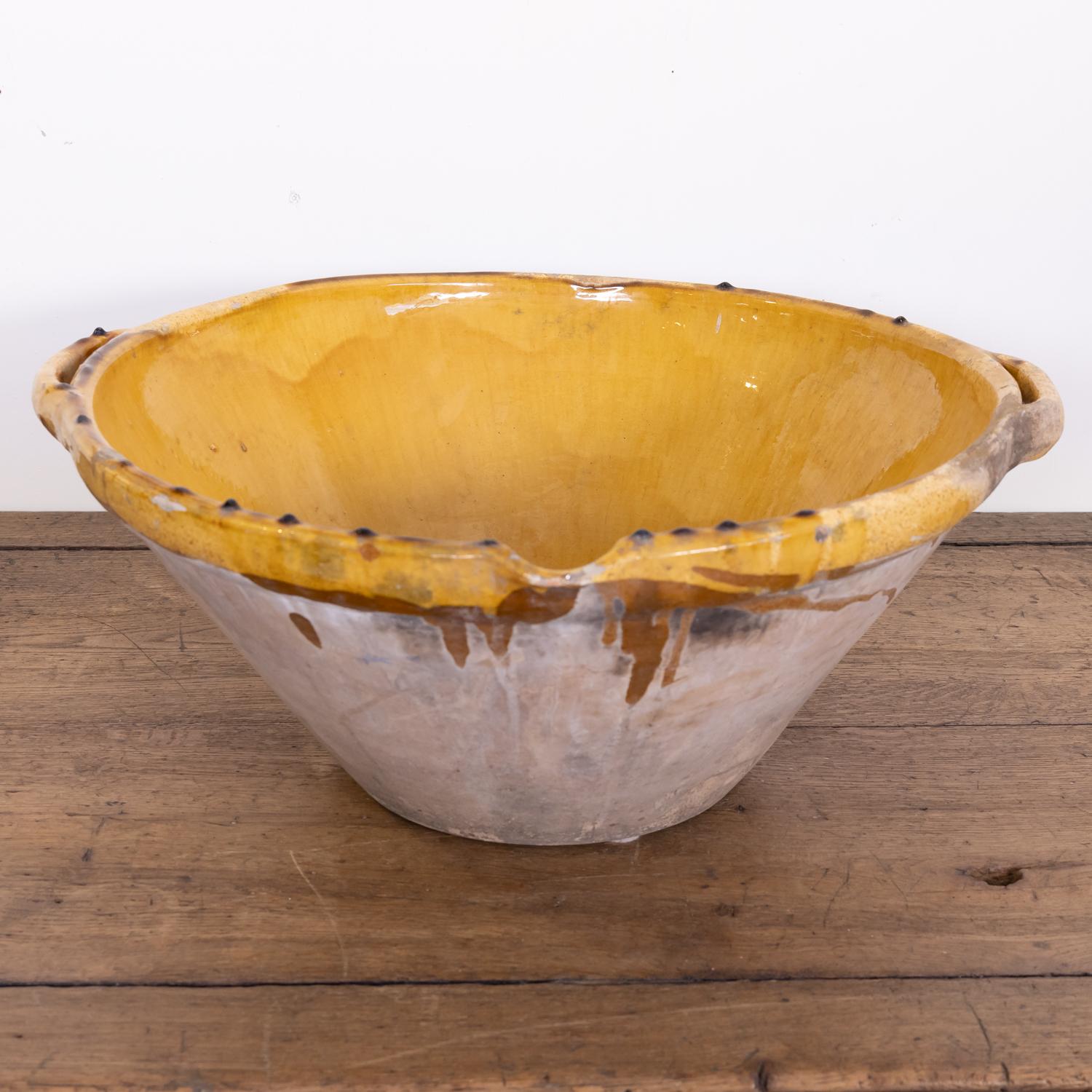 A large 19th century French terracotta tian bowl complete with both handles and pouring spout having an unglazed exterior and a beautiful mustard yellow glaze to the interior and lip, circa 1870s. Earthernware tian bowls like this are considered