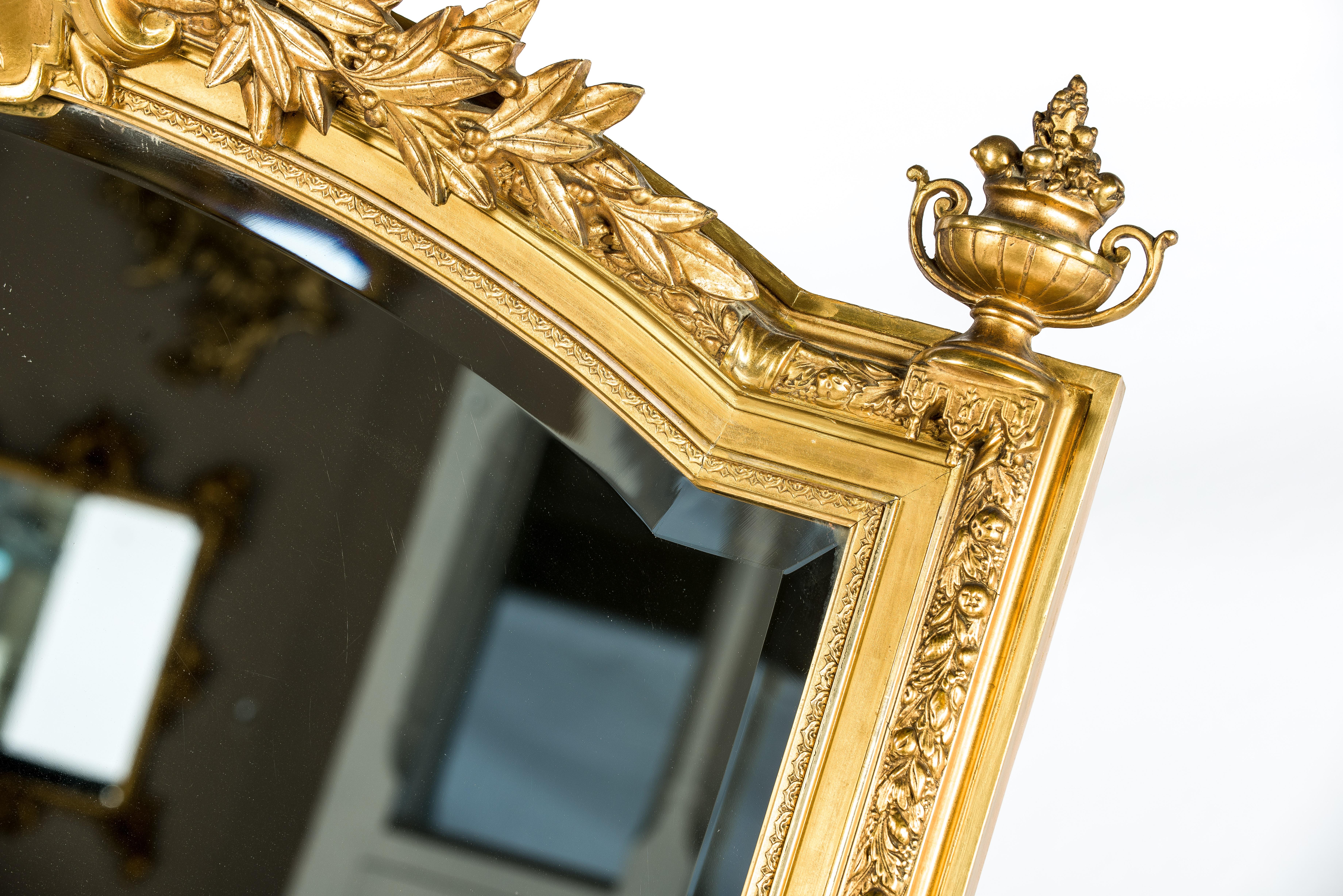 This beautiful large mirror was made in Northern France at the end of the 19th century. The mirror frame has a pine base smoothened with gesso and decorated with plaster mesh reinforced ornaments. The piece has an arched top with an elaborate crest