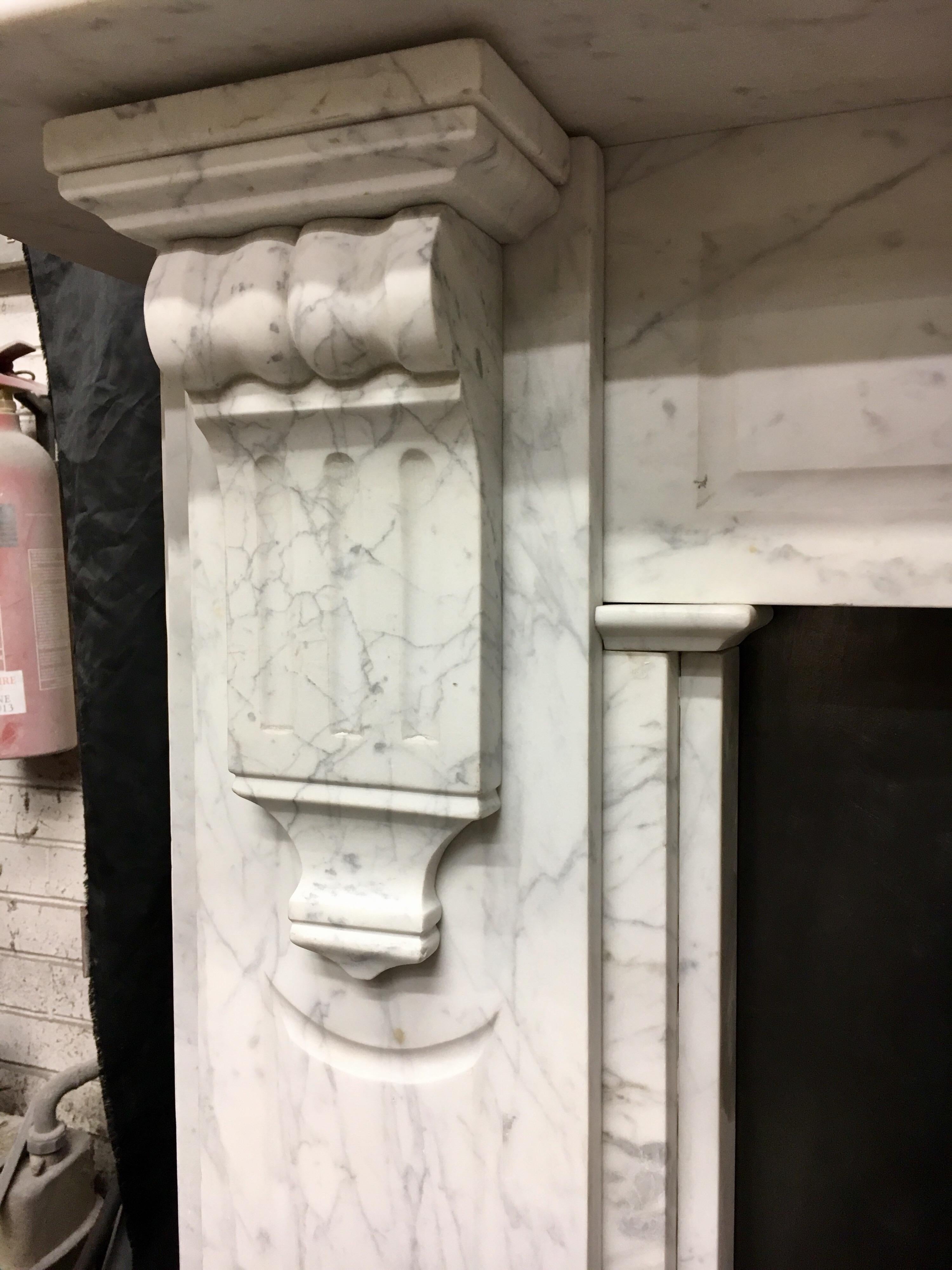 A large and splendid mid-Victorian antique 19th century Carrara marble fireplace surround, of superb quality and colour. A wide scalloped shelf sits above a panelled frieze displaying great veining, flanked by well carved bobbin & fluted corbels