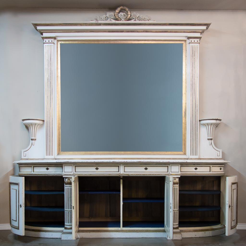 Monumental antique oak sideboard / server from a Danish mansion, circa 1860-1880. Grand in every way, the massive mirror is crowned with a carved laurel wreath and ribbon. The lower sideboard has 4 cabinet doors which open to reveal storage area