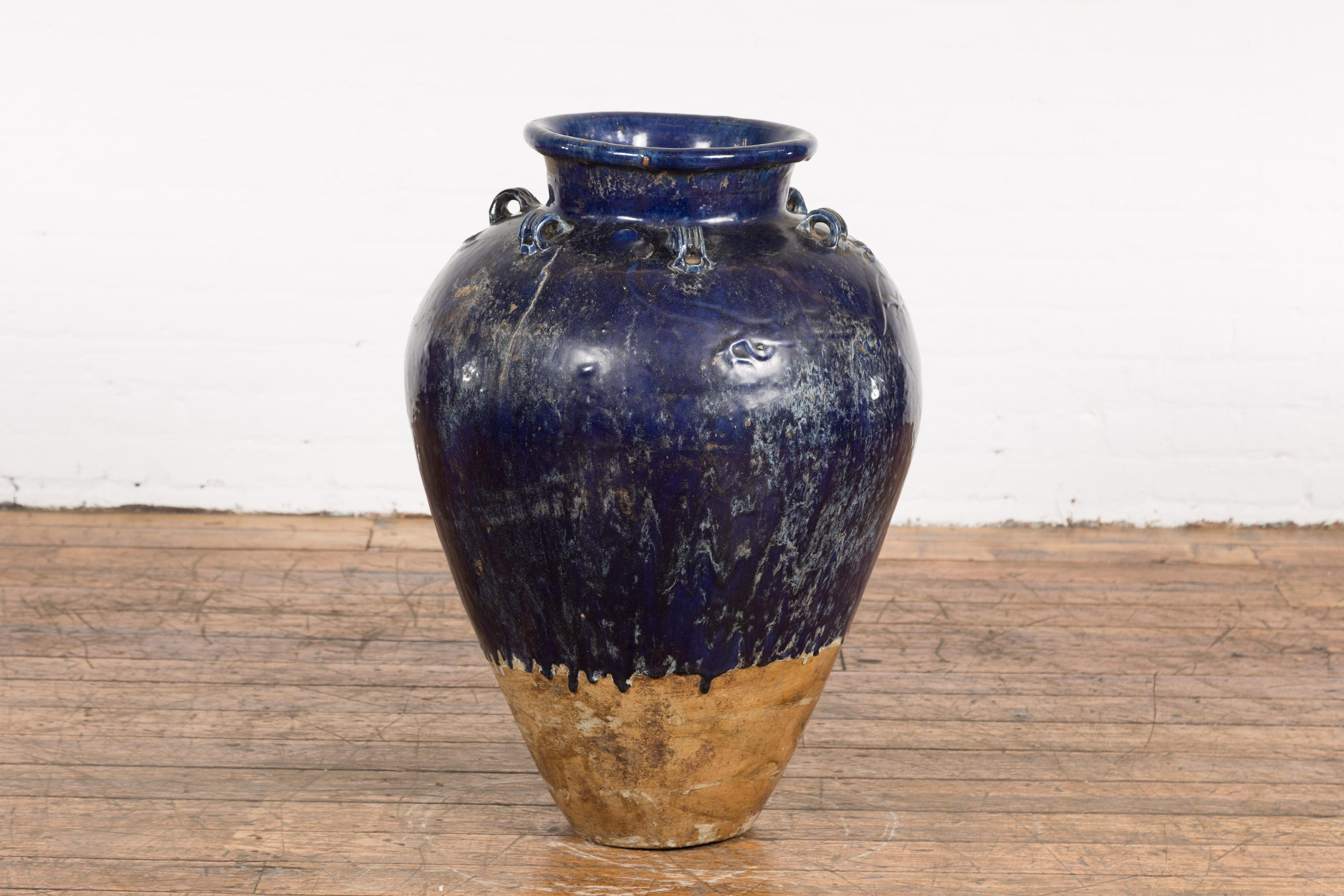 A large antique Thai cobalt blue glazed Martaban jar from the 19th century, with petite swan neck loops, raised dragon motifs and tapering lines. This large antique Thai cobalt blue glazed Martaban jar from the 19th century is an exceptional blend