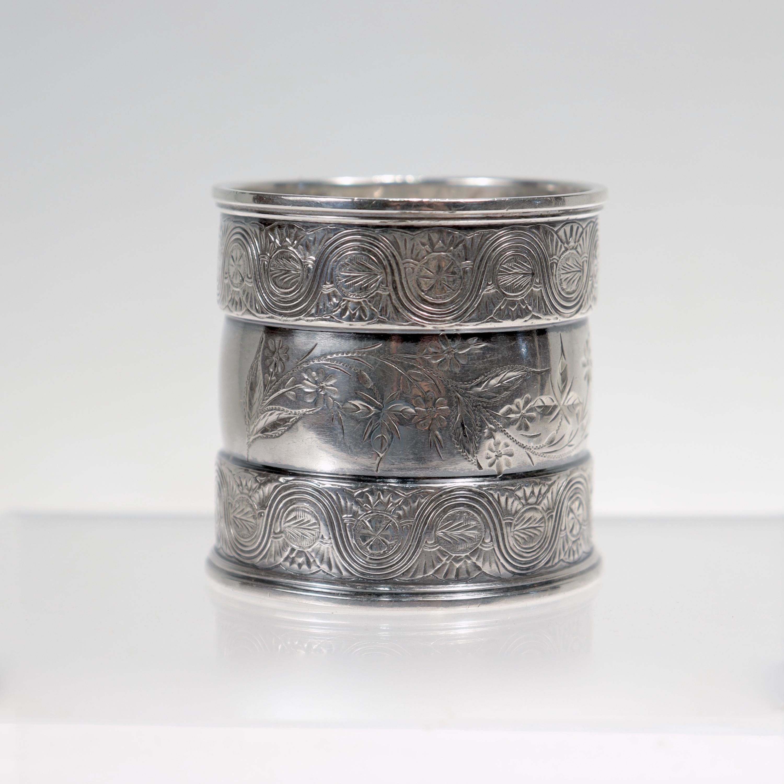 A fine antique Aesthetic Movement sterling silver napkin ring.

By Gorham.

With engraved floral devices to the center that is flanked on both sides by outer rings with intricate engraved line work.

Marked for Gorham / Sterling / 1490 / D to the