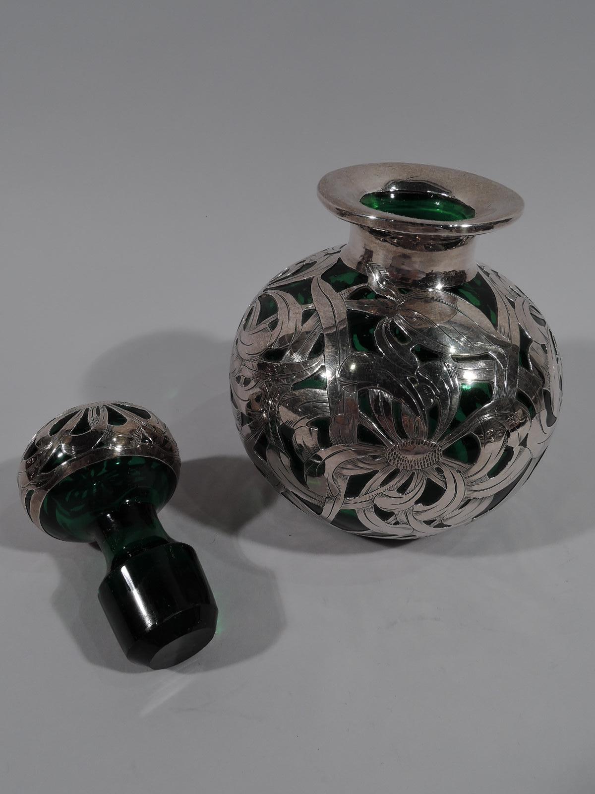 Large American Art Nouveau green glass perfume bottle with engraved silver overlay. Globular with short neck and everted rim in collar. Ball stopper. Overlay in dense and dynamic flower head pattern with interlaced and overlapping petals and