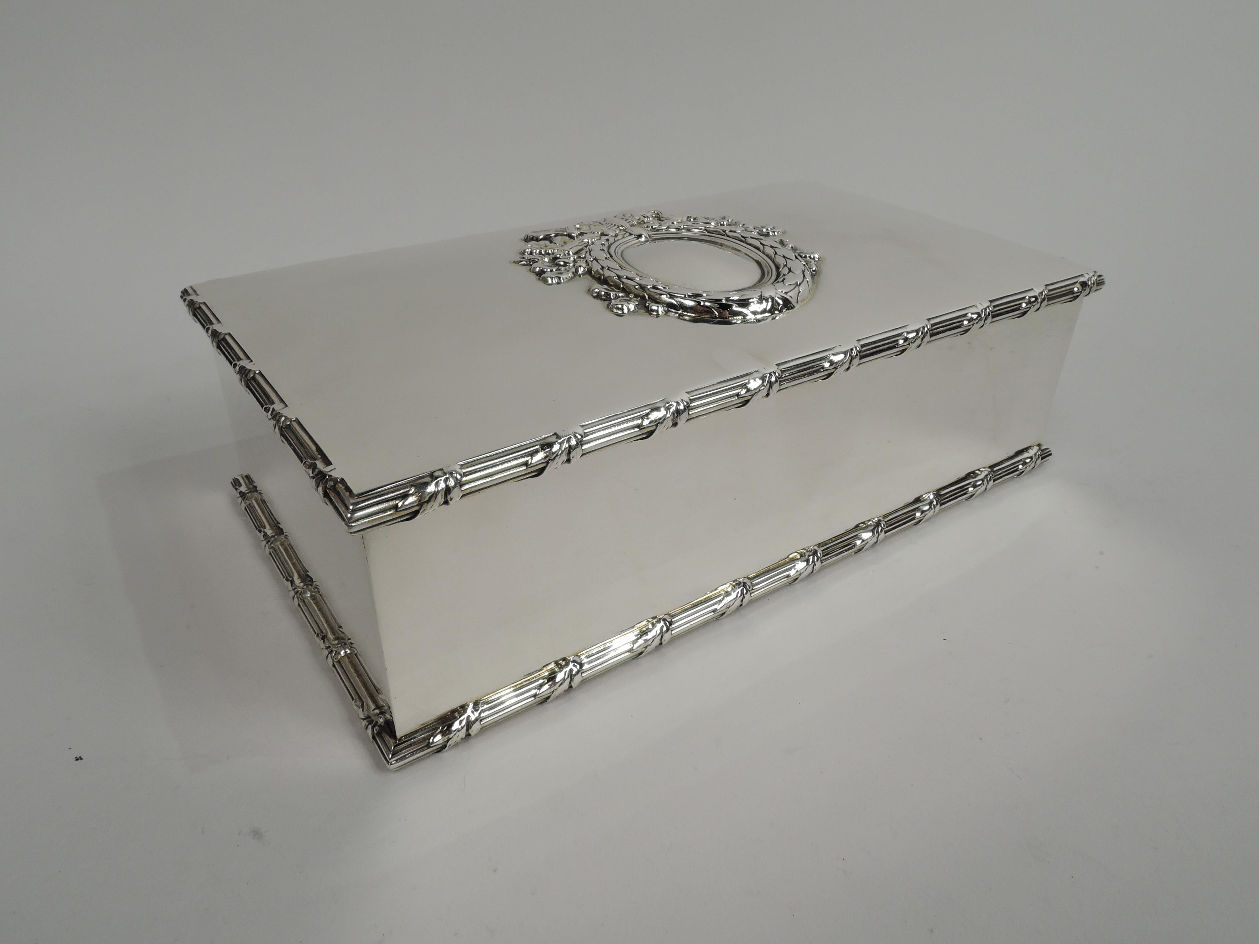 Large Edwardian Regency sterling silver keepsake box. Made by Howard & Co. in New York in 1900. Rectangular with straight sides and crisp corners. Cover hinged; top has centrally applied imbricated-leaf oval frame (vacant) with surrounded by