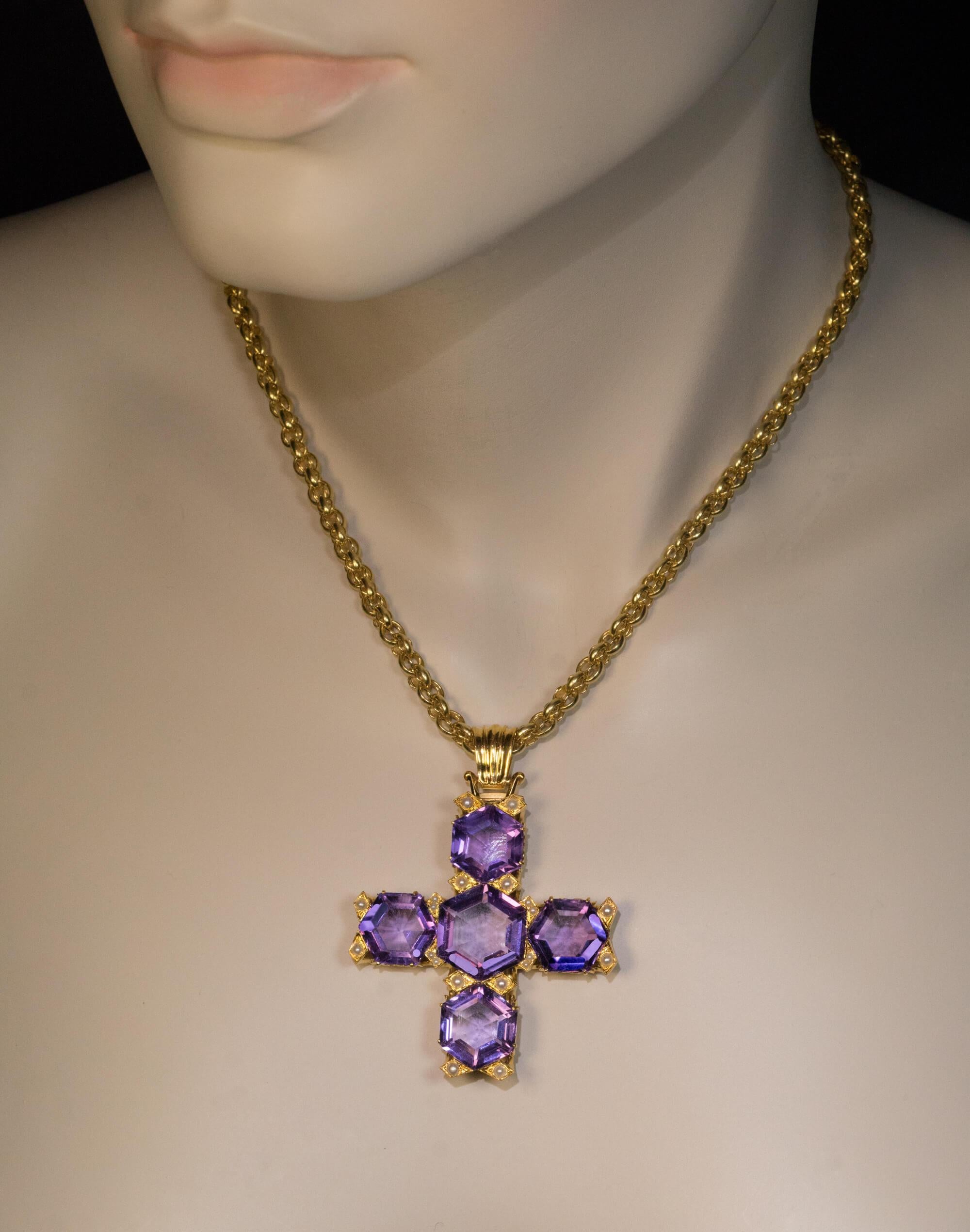 Circa 1890  This unusual late Victorian era large 18K gold cross pendant is embellished with five step cut hexagon shape amethysts of light to medium purple color. The amethysts are accented by seed pearls.  The cross measures (without bail) 48 x 46