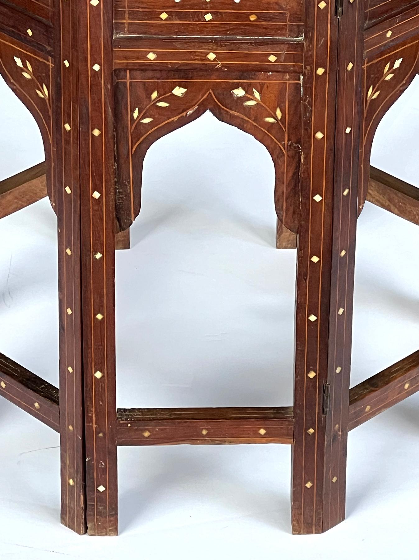 originally used as traveling tea tables for the British in India; the octagonal top with central eight-pointed star medallion surrounded by floral and foliate motifs within a foliate vine perimeter band; raised on a hinged base with arabesque