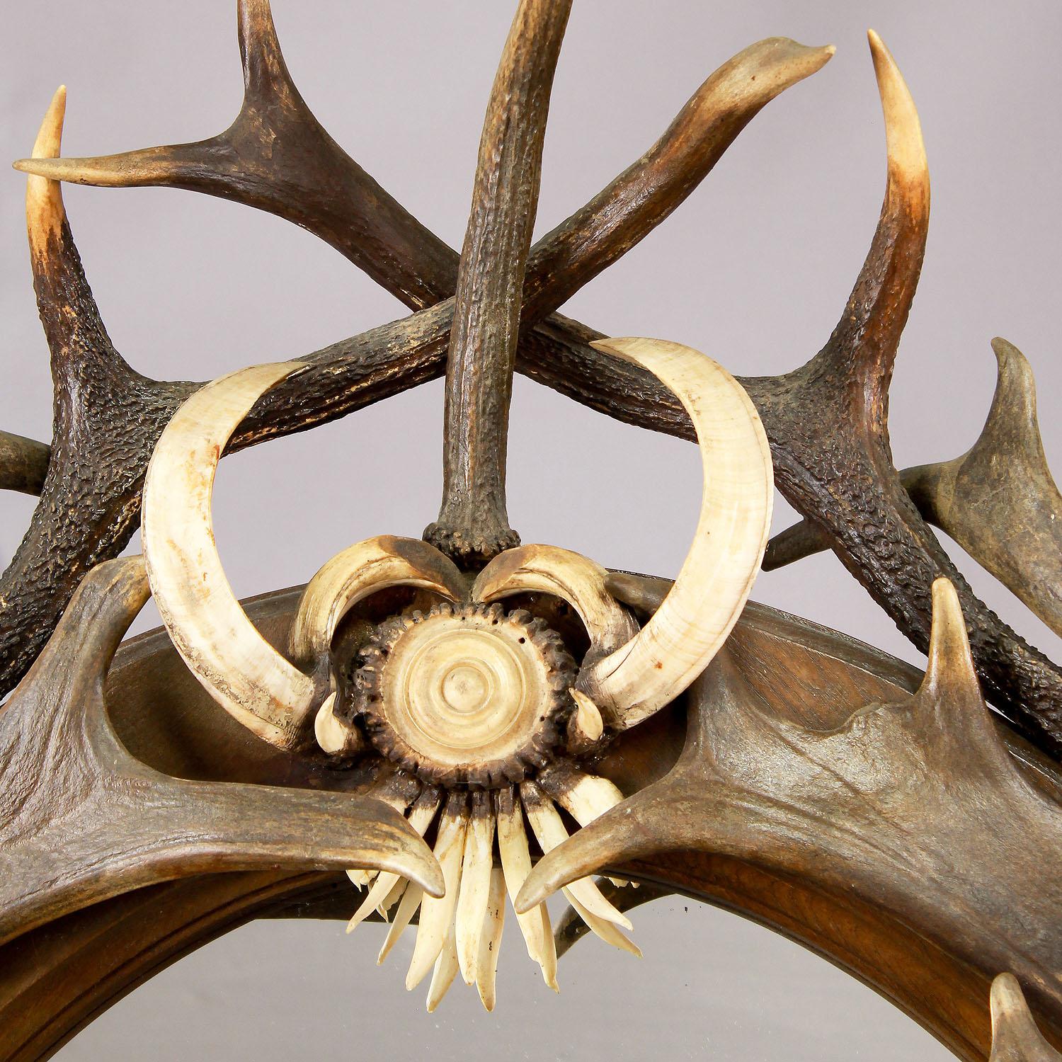 Large antique antler standing mirror, Germany, ca. 1890

A great antique Black Forest antler standing mirror manufactured in Germany around 1890. An oval wooden frame richly decorated with antlers from the deer, the fallow deer, wild boar tusks and