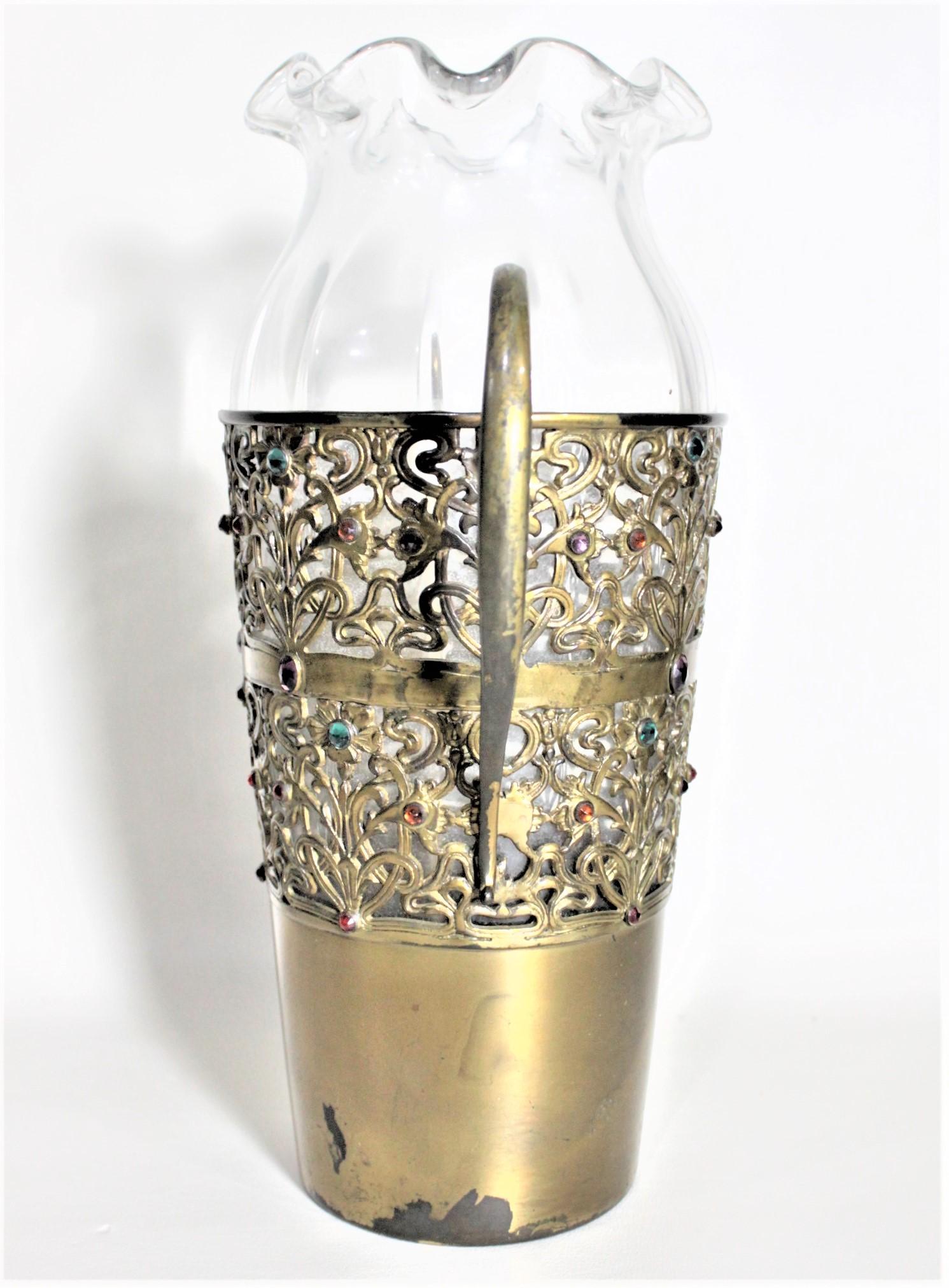 Ce grand vase en verre ancien a été fabriqué par l'Apollo Silver Co. de New York vers 1870 dans le style victorien. Le vase transparent est serti dans une monture en métal filigrané patiné laiton avec des bijoux incrustés en verre multicolore. Le