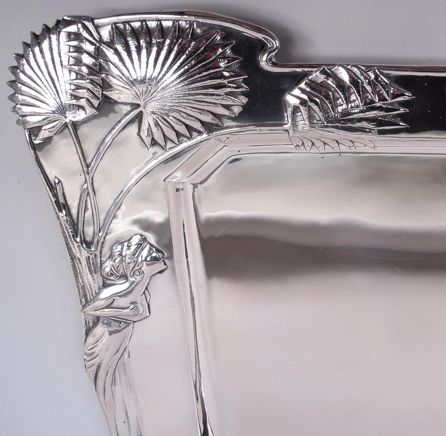 Gran bandeja austriaca de plata Art Nouveau 800, hacia 1900. Pozo rectangular con esquinas inclinadas; hombro ancho con borde moldeado en serpentina y latigazo. Ornamento en relieve: nenúfares desbordantes de tallos enmarañados y cabezas de flores