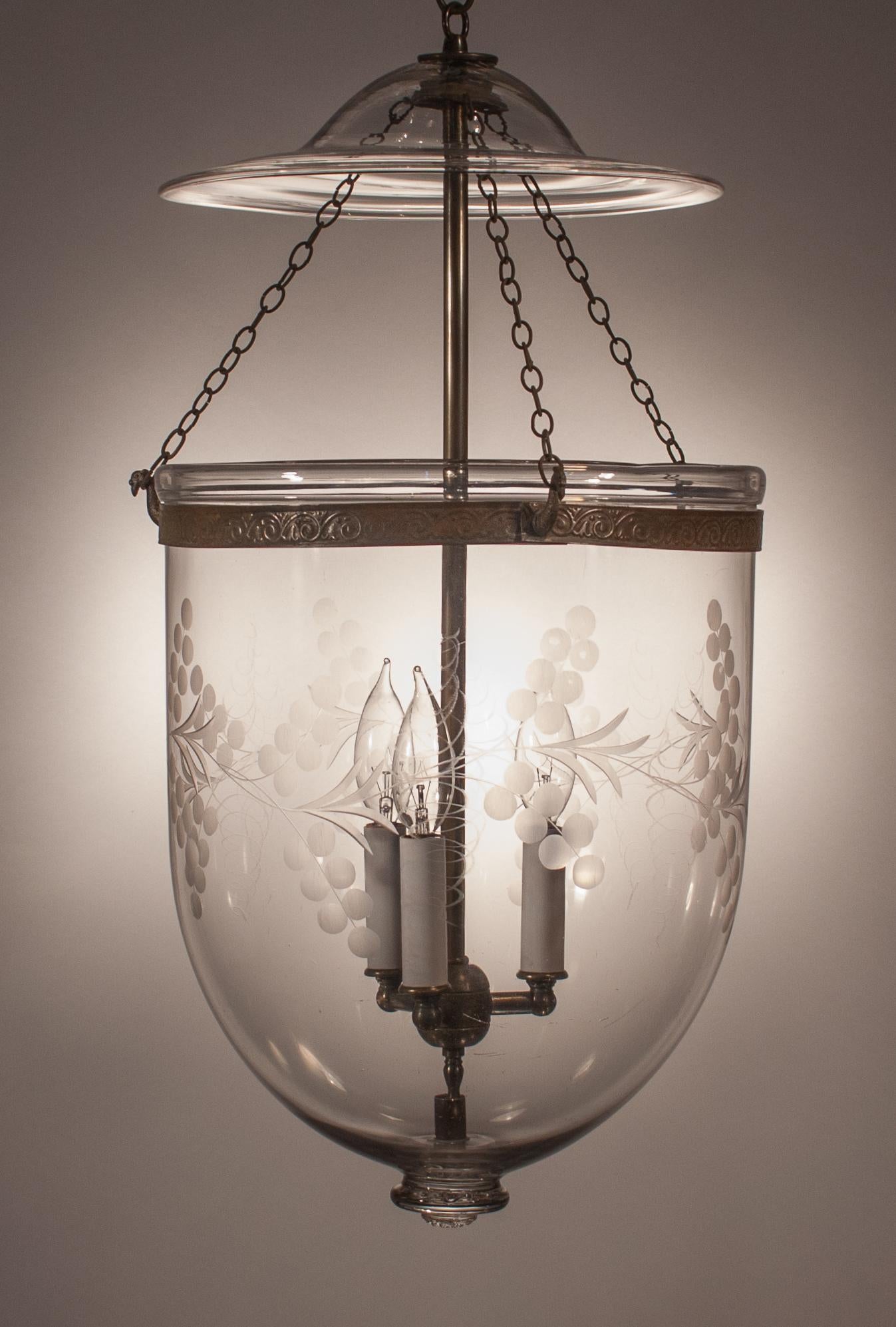A larger-sized, circa 1870 English bell jar lantern with beautiful form that is complemented with an etched vine motif. The lantern has its original smoke bell/lid. The embossed brass band, which has a wave pattern, was replaced to safeguard against
