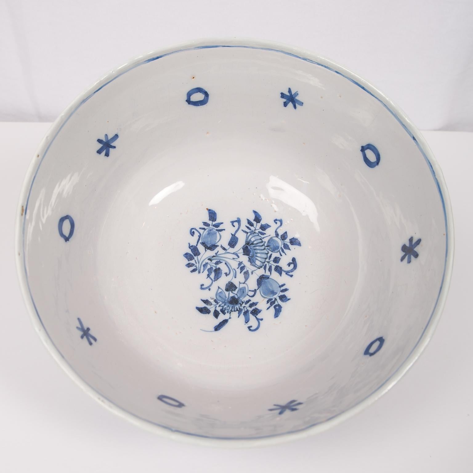 A large antique Blue and White Dutch Delft punch bowl made in the 18th century, circa 1780. This charming bowl is painted in a soft cobalt blue, decorated on the outside with a wide band of delicate flowers and vines. Along the top and near the