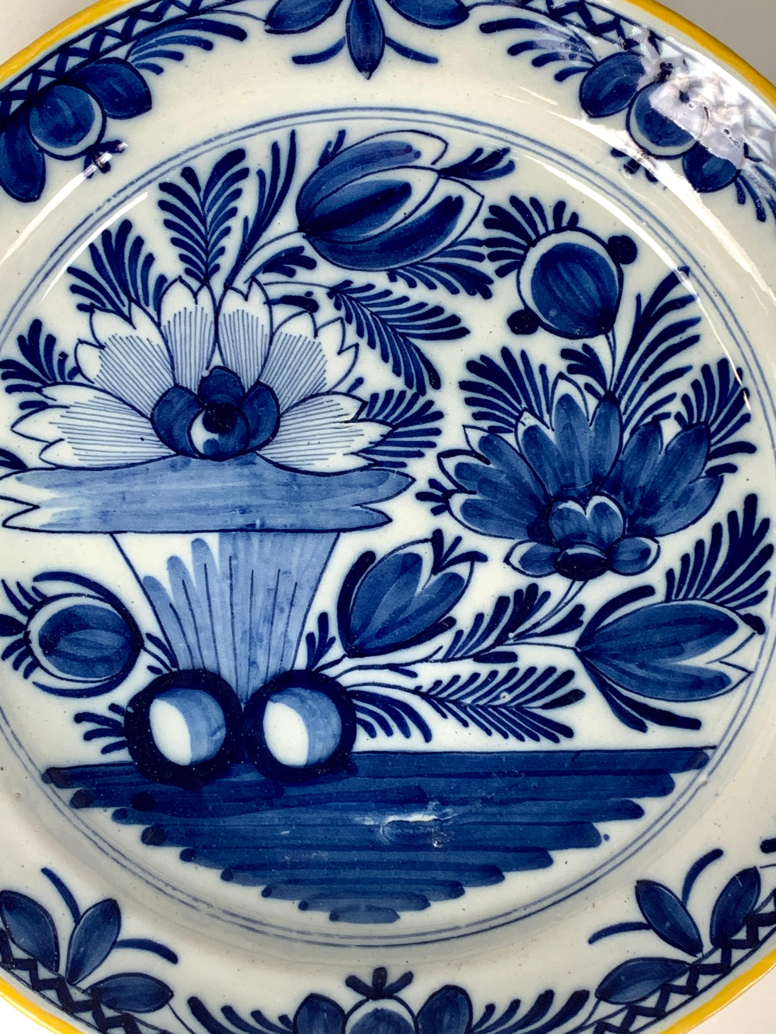 An antique blue and white Dutch Delft charger showing tulips and peonies. 
The bright cobalt blue is splendid on the bright white tin glaze background.
 The border is filled with a floral design. A zig-zag design appears just before the edge,
