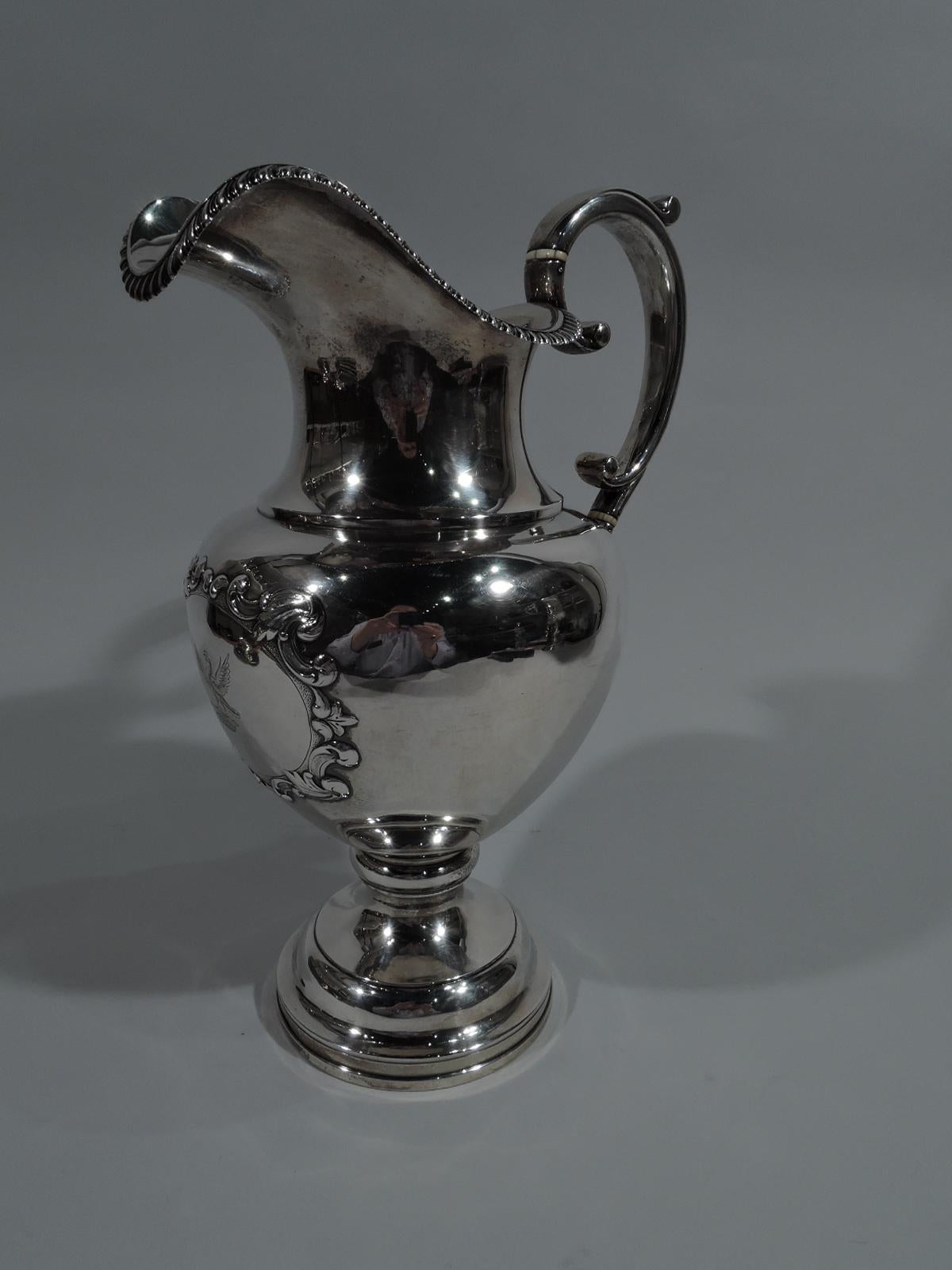 Large coin silver wine ewer. Made by Jones, Lows & Ball, who were active in Boston from 1839-1846. Ovoid bowl on stepped foot with gadrooned helmet mouth and high-looping capped scroll handle. On front oval cartouche bordered by chased scrolls on