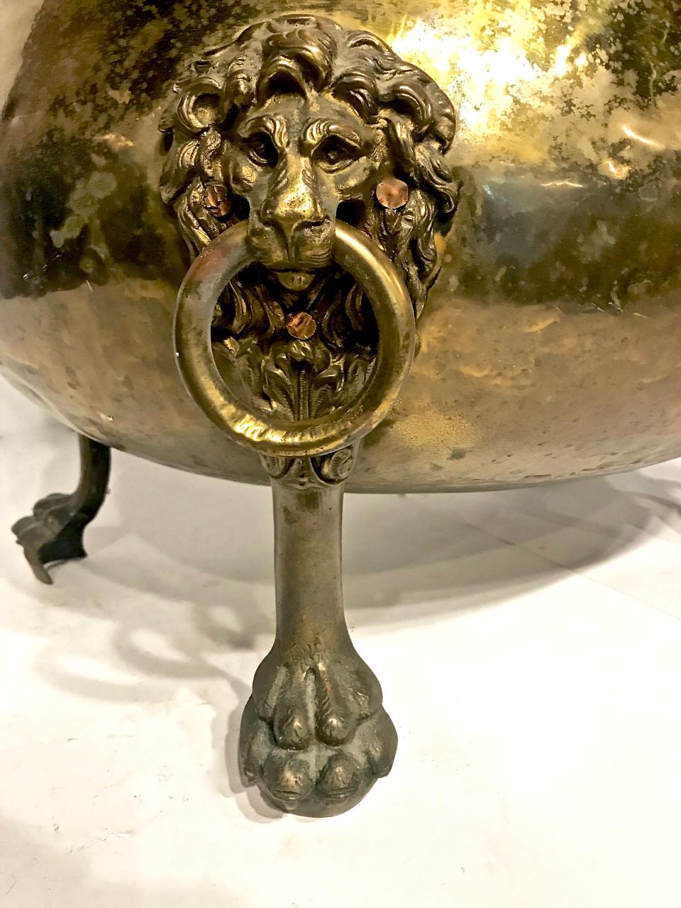 This is an unusually large 19th century. Solid brass log bin that is detailed with finely elaborated lion mask handles and paw feet. This vessel would be a distinctive towel holder for a gentleman's bathroom, as well as a planter or elegant catchall.