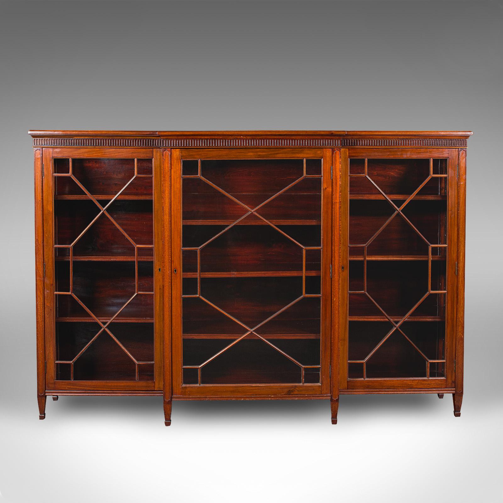 This is a large antique breakfront bookcase. An English, walnut display cabinet with astragal glazed doors in Georgian revival taste, dating to the Victorian period, circa 1870. A stately and refined example with superb proportion, ideal for the