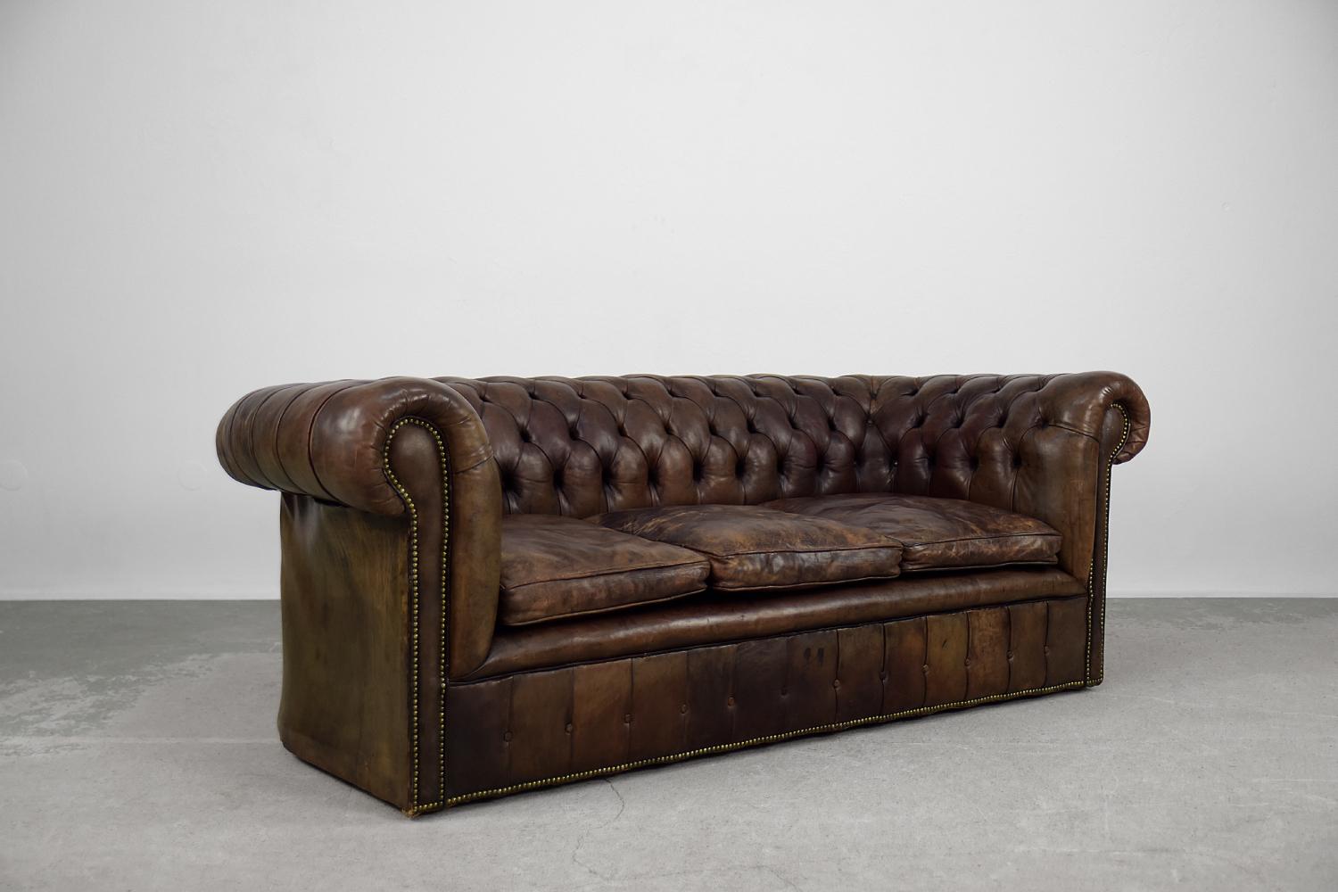 Dieses dreisitzige Chesterfield-Ledersofa wurde in den 1920er Jahren in England hergestellt. Es ist eines der bekanntesten Möbelstücke der Welt. Das Gestell des Sofas ist aus Massivholz und mit Naturleder in verschiedenen Brauntönen gepolstert. Sie