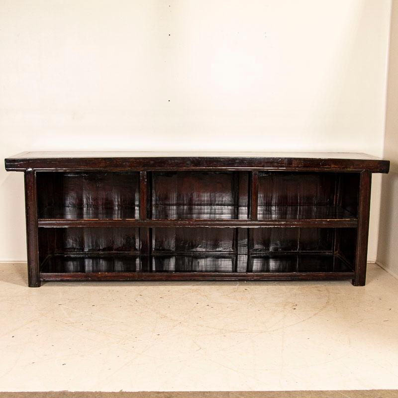 This 9' long sideboard still maintains its original dark stained and lacquered finish, traditional in China. The unique size and configuration with open storage allows it to be used in a variety of settings as a console table, buffet/server, counter