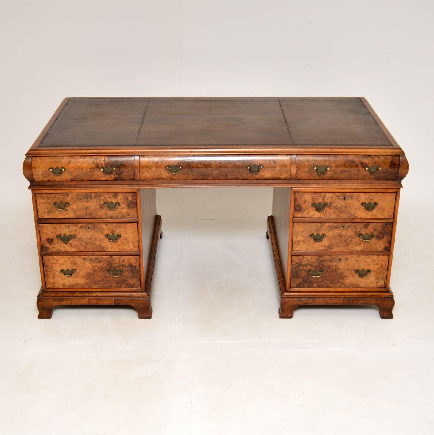 An outstanding antique pedestal desk in burr walnut with an inset leather top. This was made in England, it dates from around the 1900-1920’s period.
It is of superb quality and is of large proportions. This model is sometimes called a cushioned