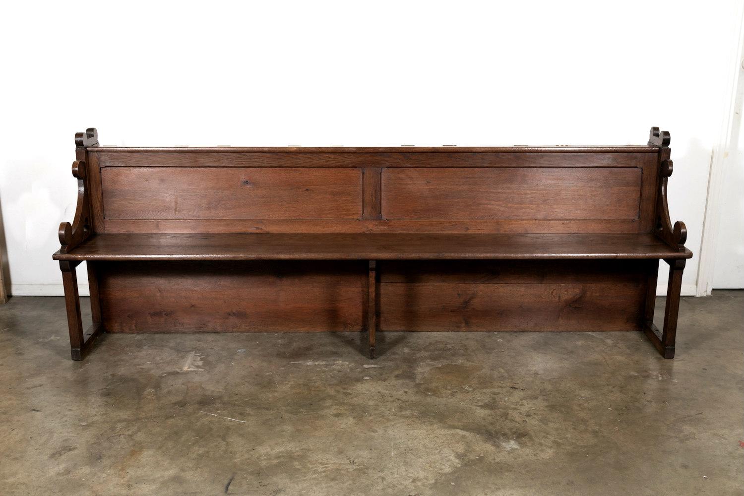 Well preserved 19th century antique French Gothic Revival period church pew handcrafted from solid oak. This large church pew features a raised panelled back with a covered Bible or hymnal storage bin and armrests having pierced trefoils.

The