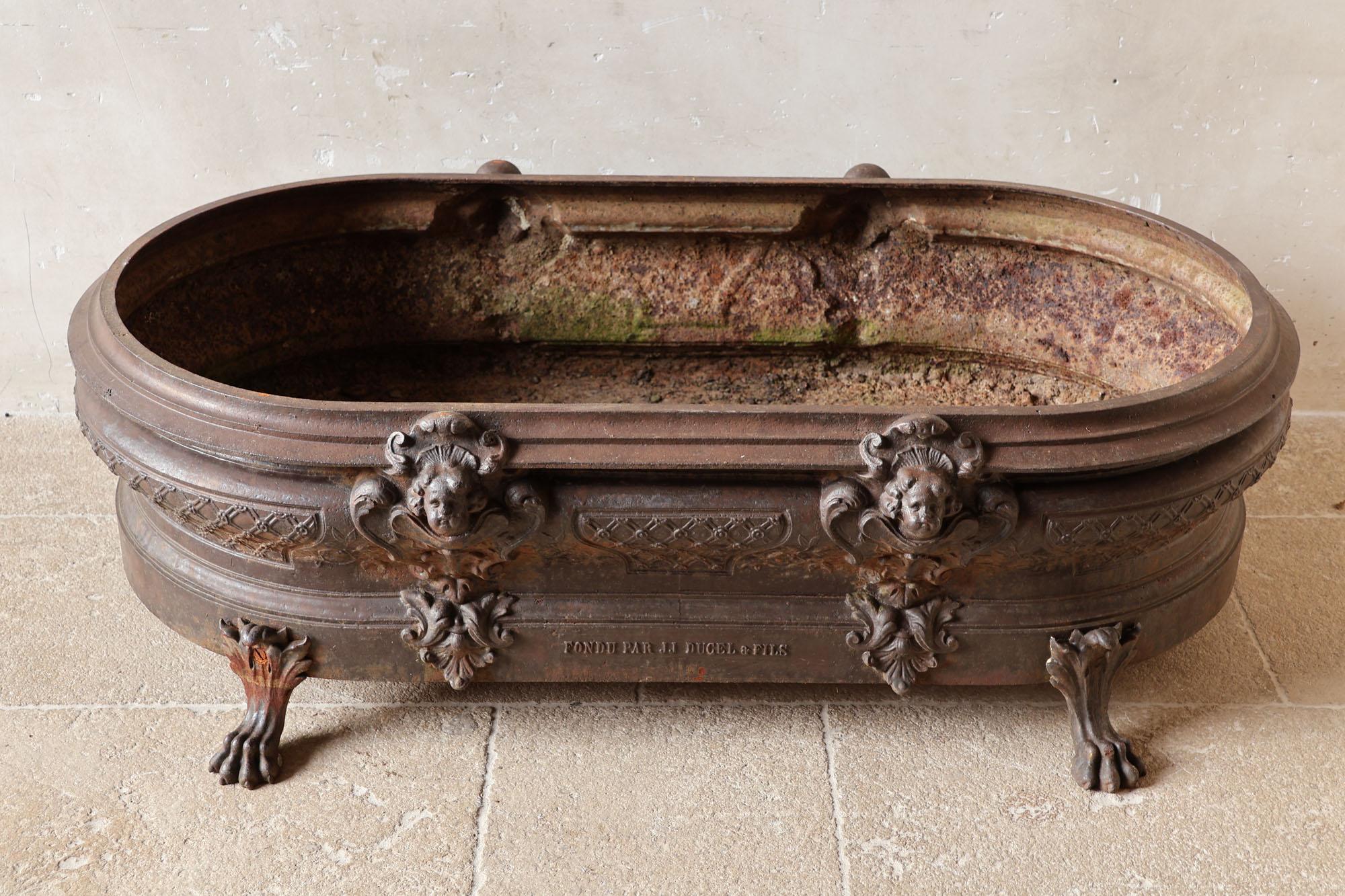 Large antique cast iron jardinière, richly decorated with angel heads and lion paws. This rare French planter was cast and stamped by J.J. Ducel Paris ± 1880. Beautiful for the entrance hall or on the terrace.

Dimensions: H 43 × L 138 × W 72 cm