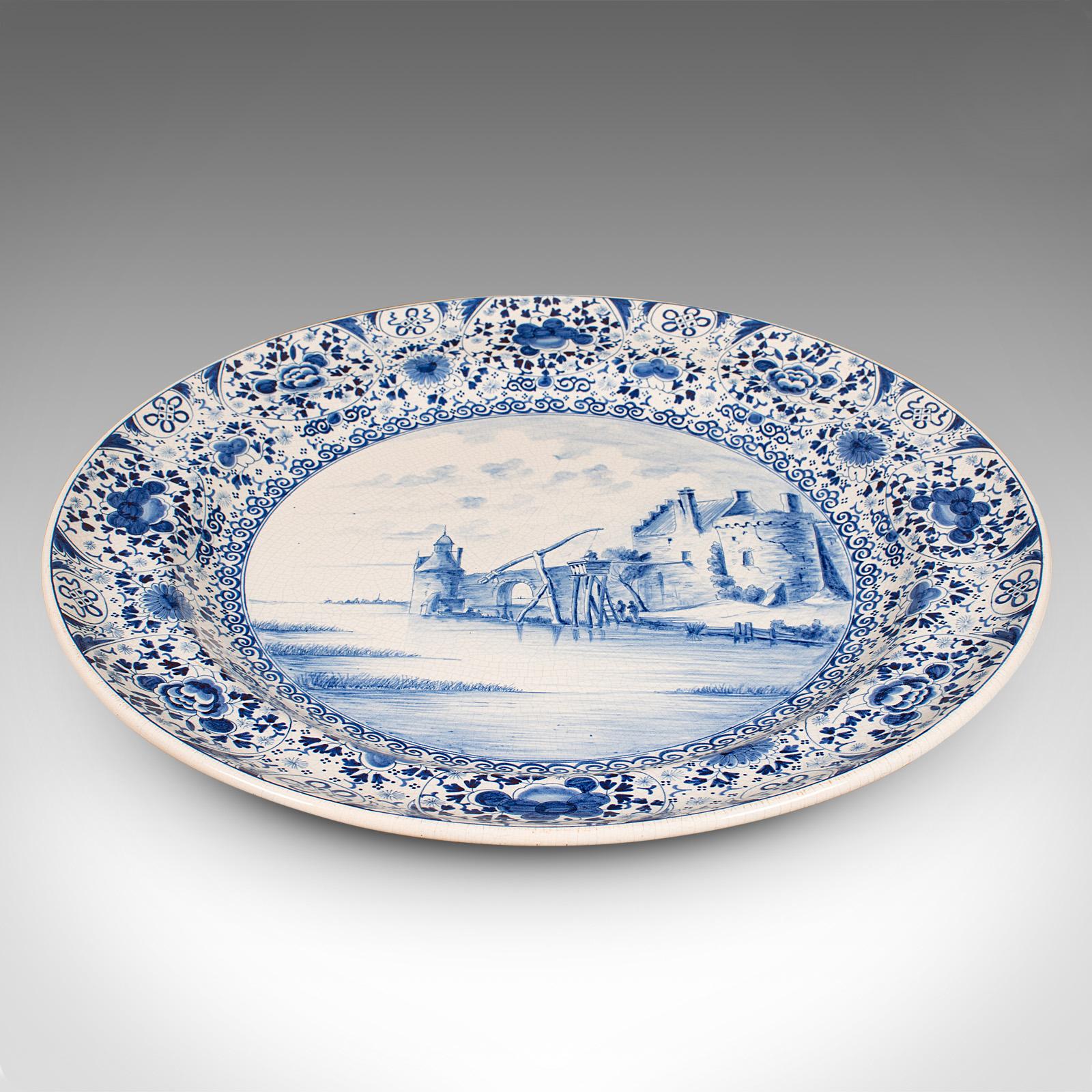 This is a large antique charger. A Belgian, ceramic serving plate with decorative finish, dating to the early 20th century, circa 1920.

Of generous proportion with a charming Delft blue & white taste
Displaying a desirable aged patina and in good