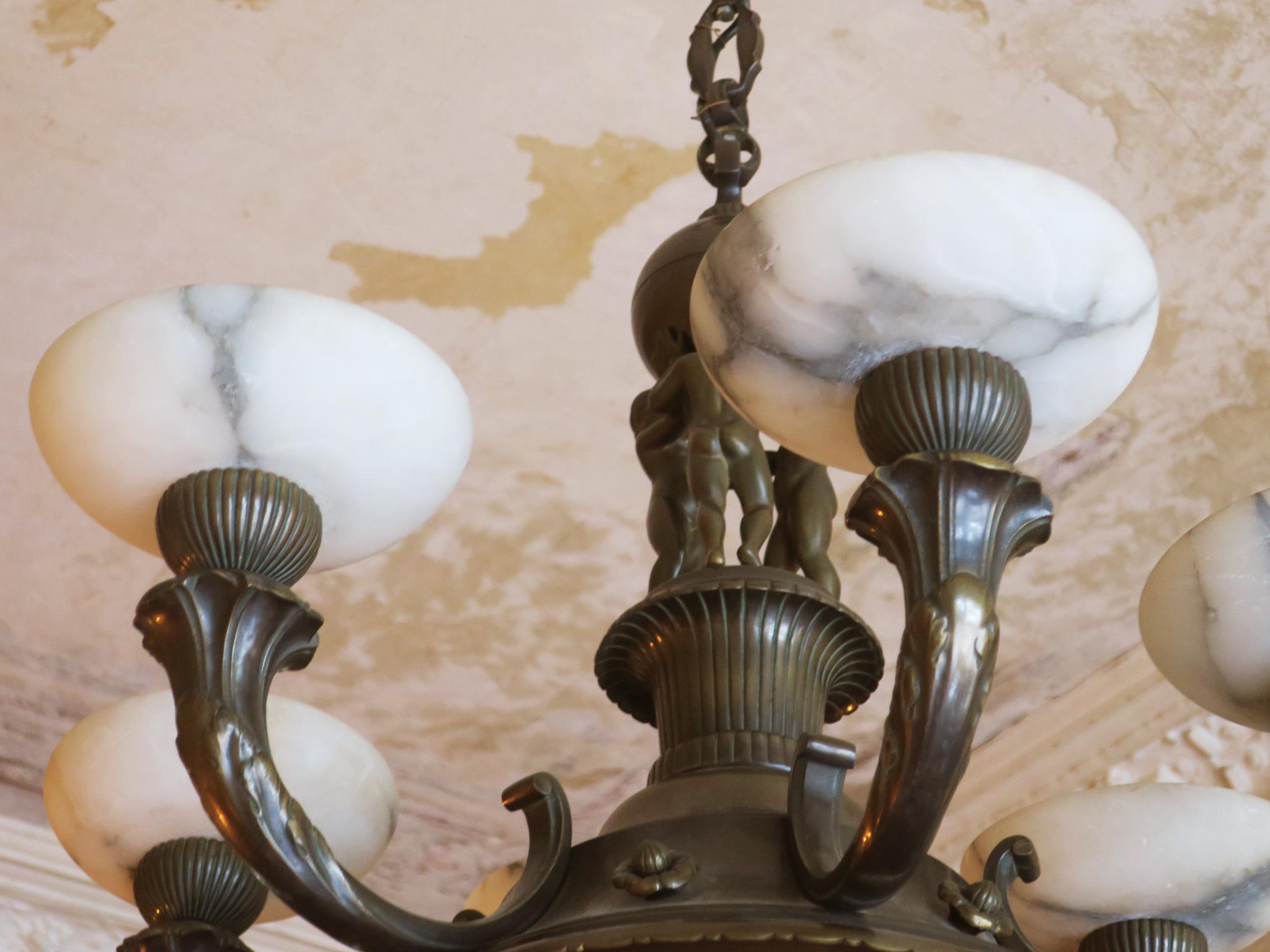 Impressive antique patinated bronze six-light chandelier with alabaster shades. The lamp features cherub figures.
Dates from about 1910-1920.
Very good vintage condition with minor signs of age and use.