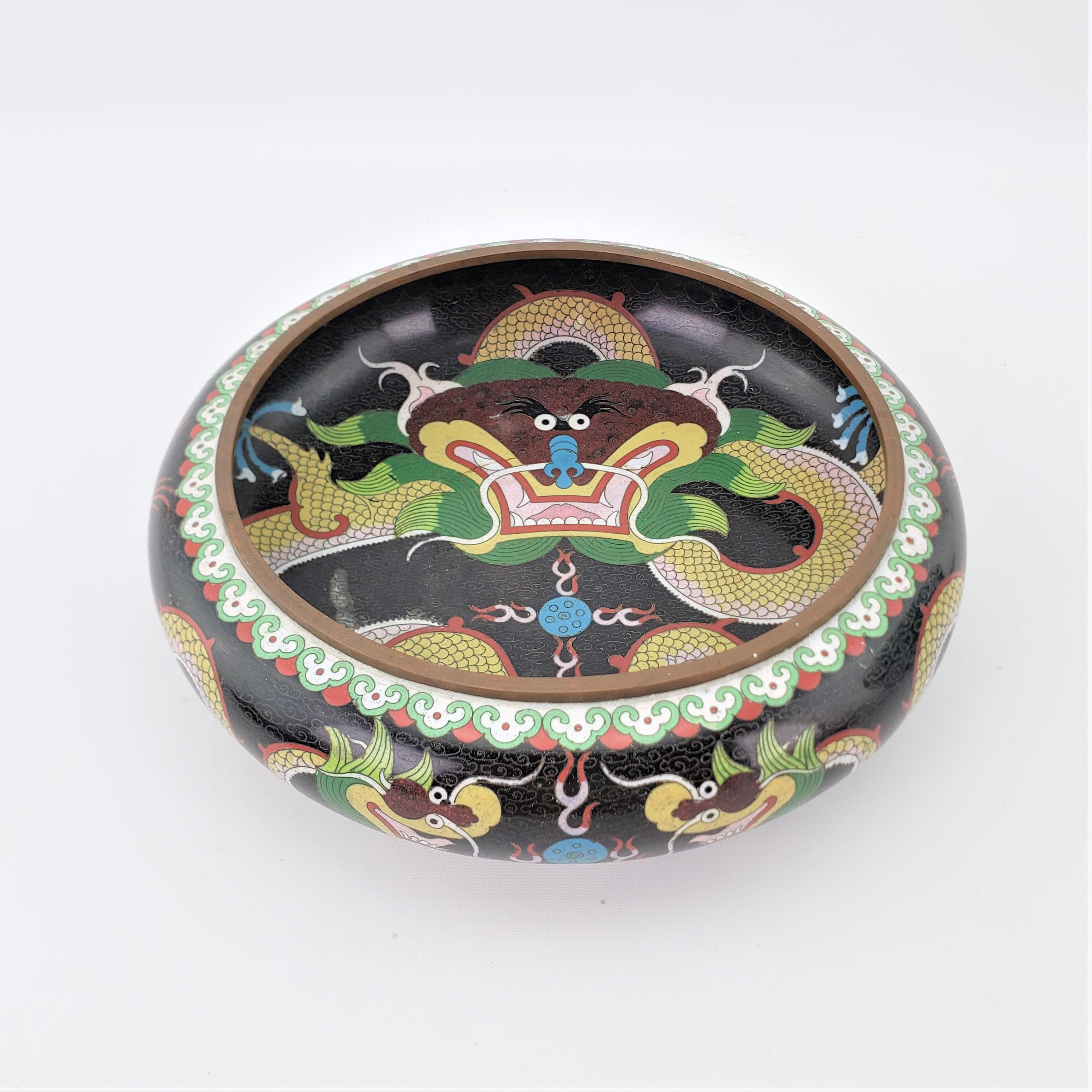 This large and very well executed cloisonnae bowl is signed by and unknown artist and originates from China in approximately 1900 in the period Chinese Export style. The bowl is done with black as the predominant color and decorated with Imperial