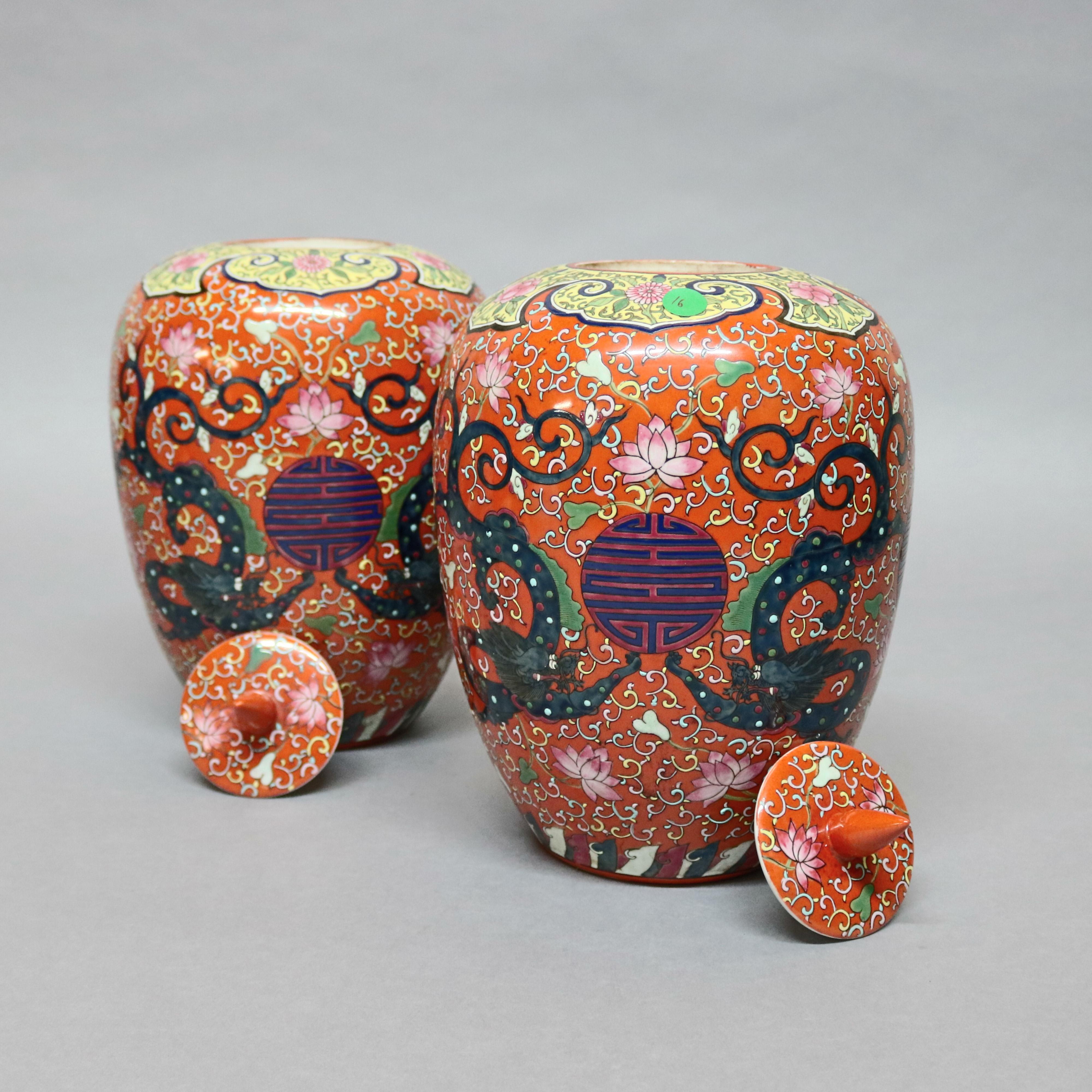 A pair of large and antique Chinese porcelain lidded urns offer hand enameled decoration with all-over scroll decoration with central 