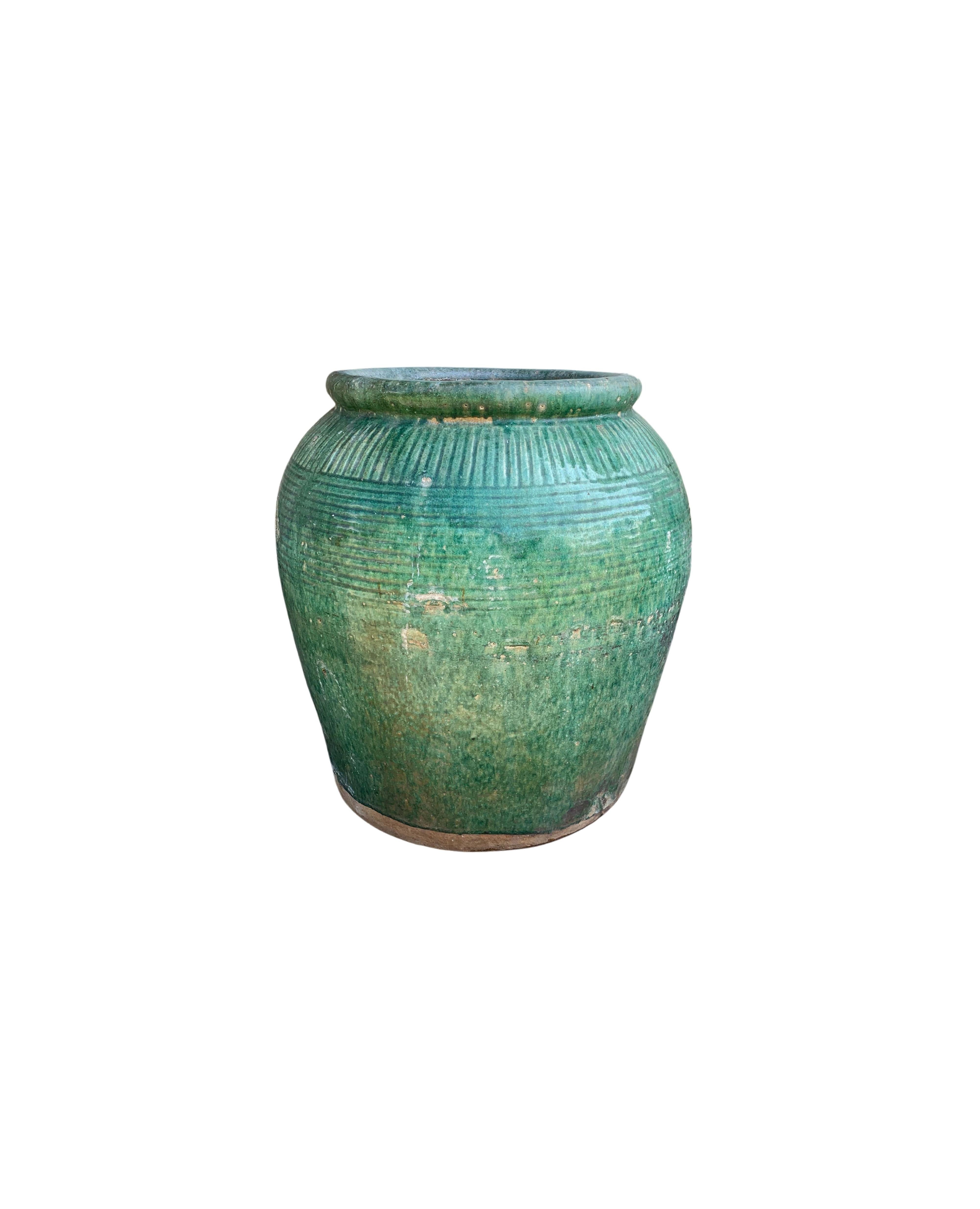 This glazed Chinese ceramic jar from the turn of the 19th Century was once used for soy sauce production. It features a wonderful green glazed finish and outer surface that features a ribbed texture. A great example of Chinese pottery, with its