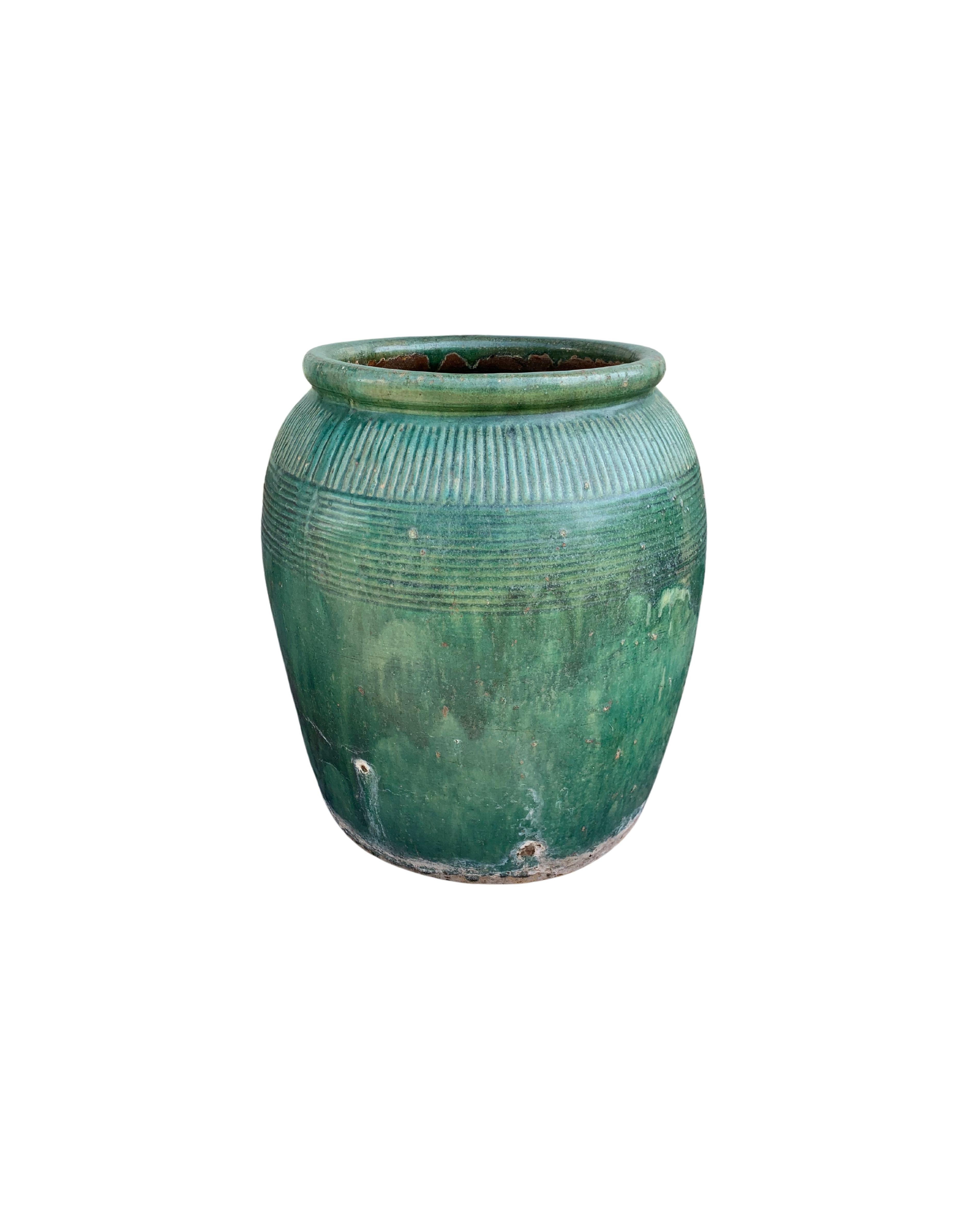 Cette jarre en céramique chinoise vernissée datant du début du XIXe siècle était autrefois utilisée pour la production de sauce soja. Il présente une merveilleuse finition émaillée verte et une surface extérieure qui présente une texture côtelée. Un
