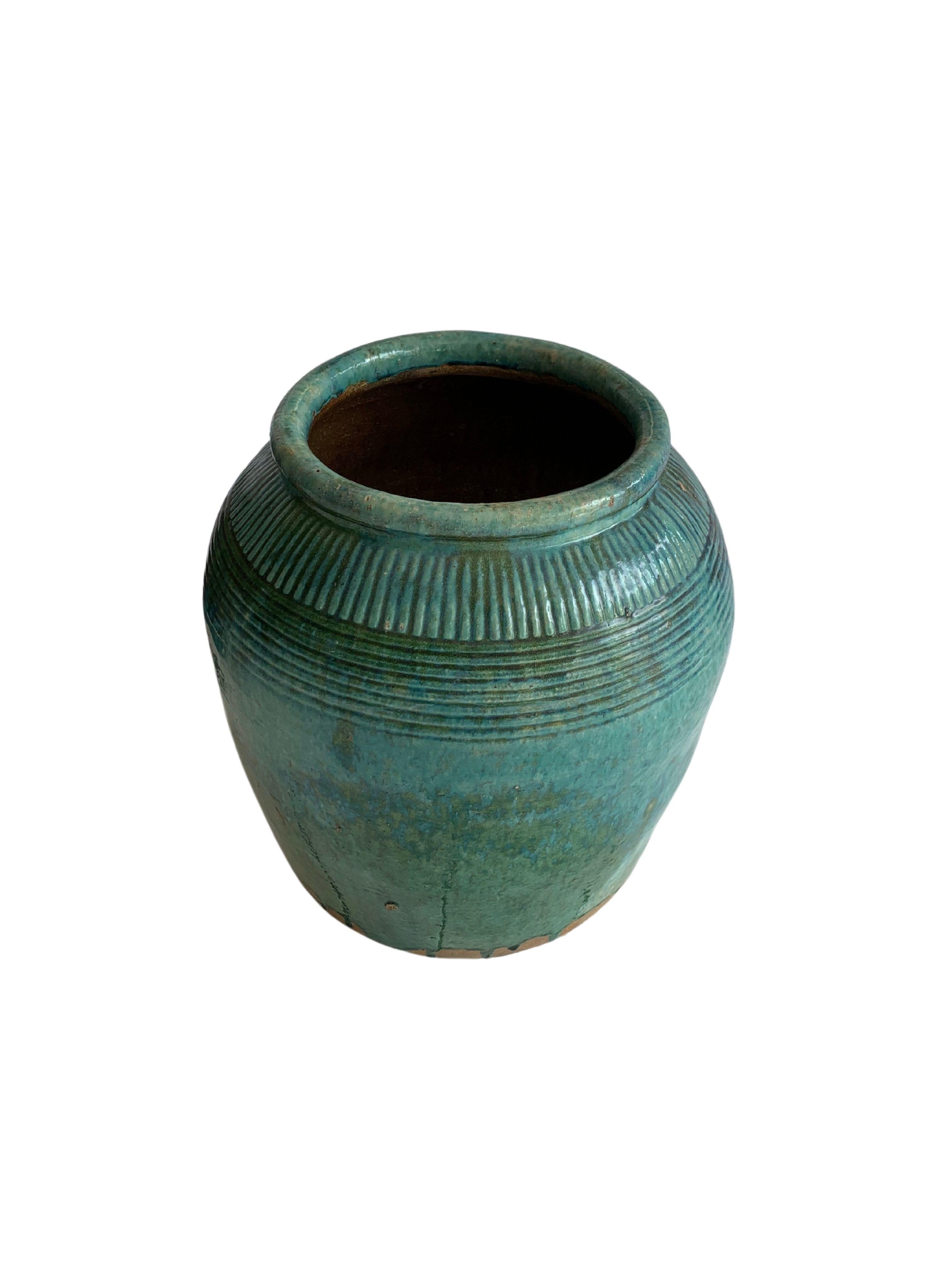 This glazed Chinese ceramic jar from the turn of the 19th Century was once used for soy sauce production. It features a wonderful green glazed (with hints of turquoise) finish and outer surface that features a ribbed texture. A great example of