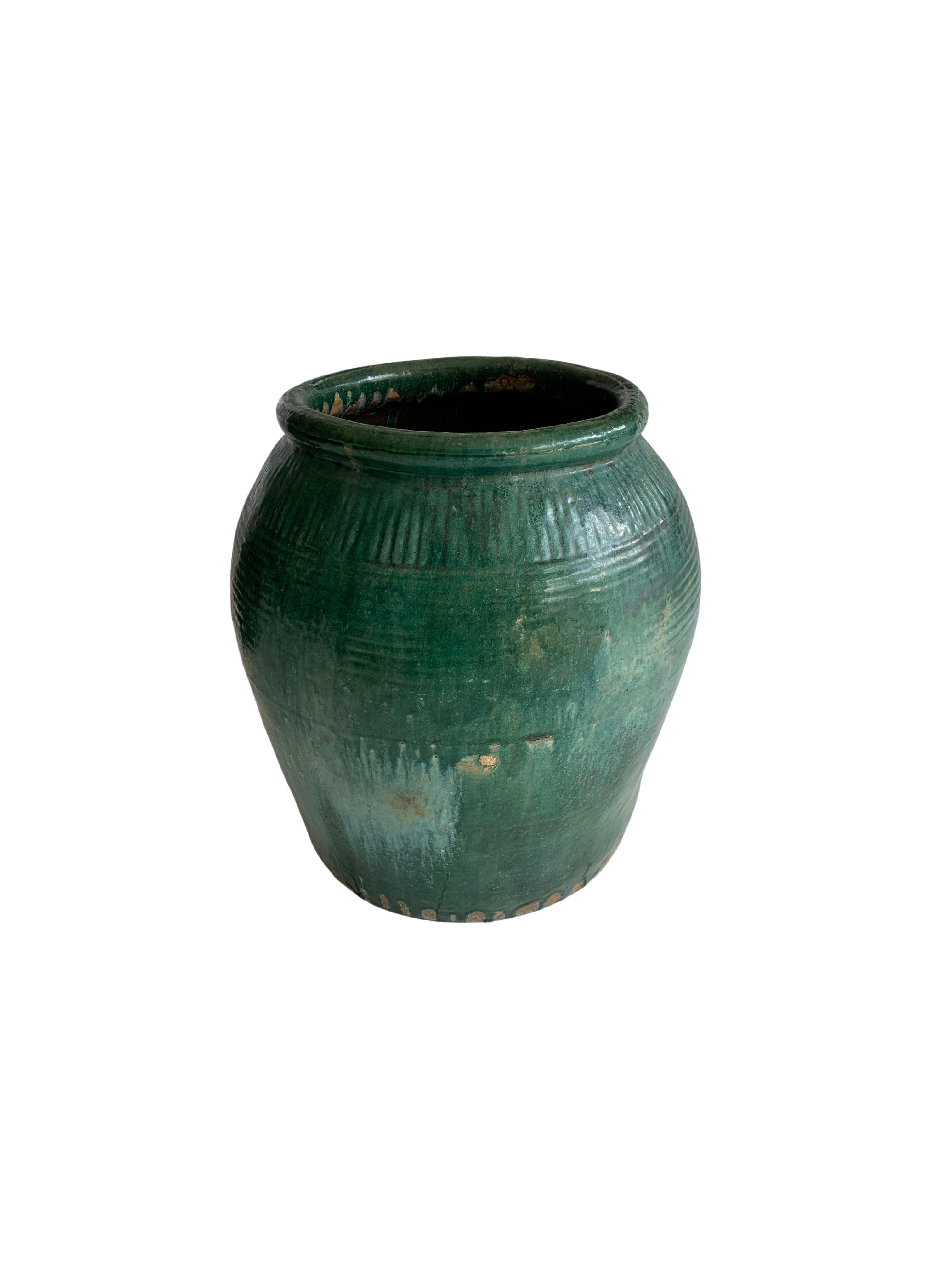 This glazed Chinese ceramic jar from the turn of the 19th Century was once used for soy sauce production. It features a wonderful green glazed finish and outer surface that features a ribbed texture. A great example of Chinese pottery, with its