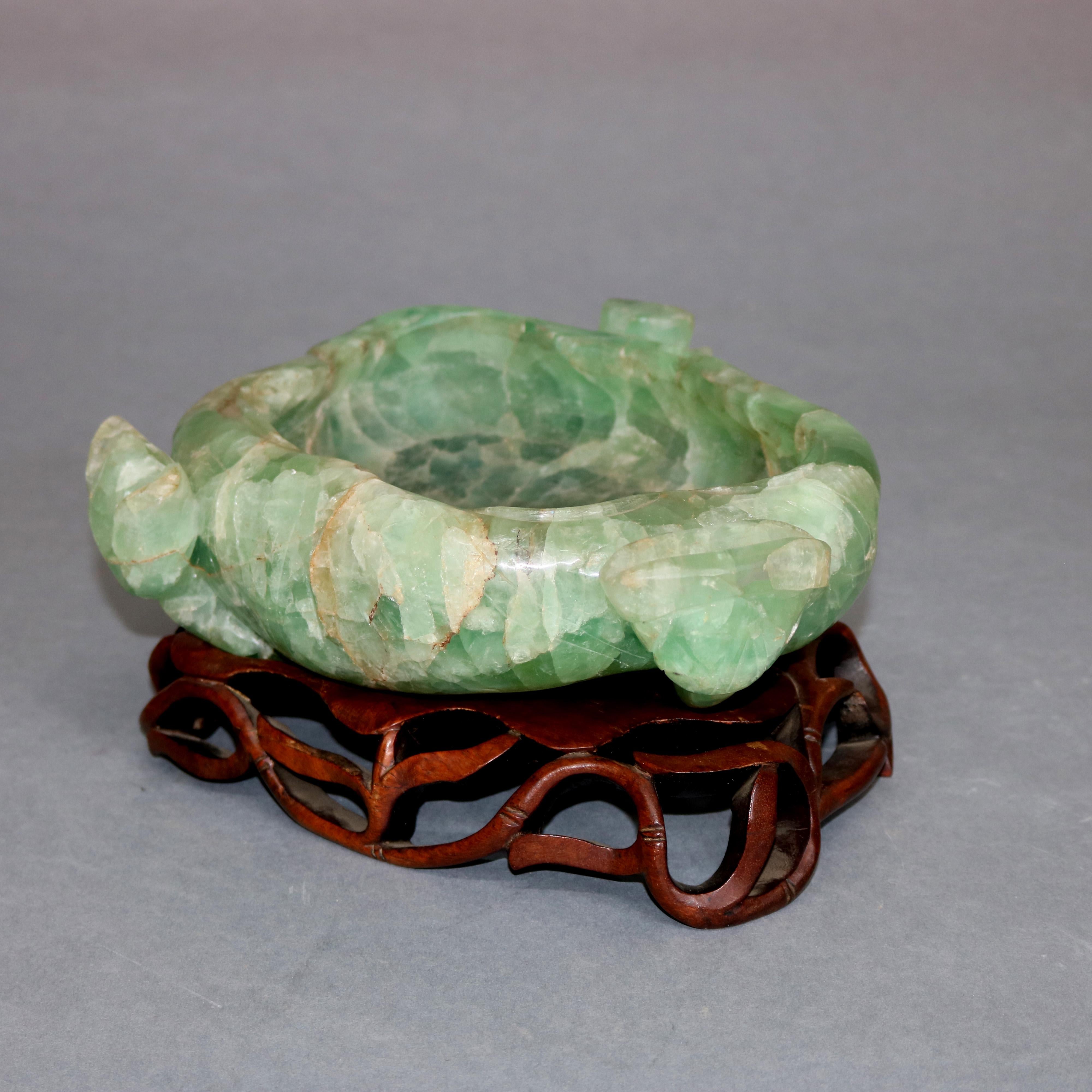 A large and antique Chinese gemstone bowl features carved jadeite in irregular and natural form seated on carved hardwood base with pierced foliate design, circa 1900

Measures: Base: 1.88