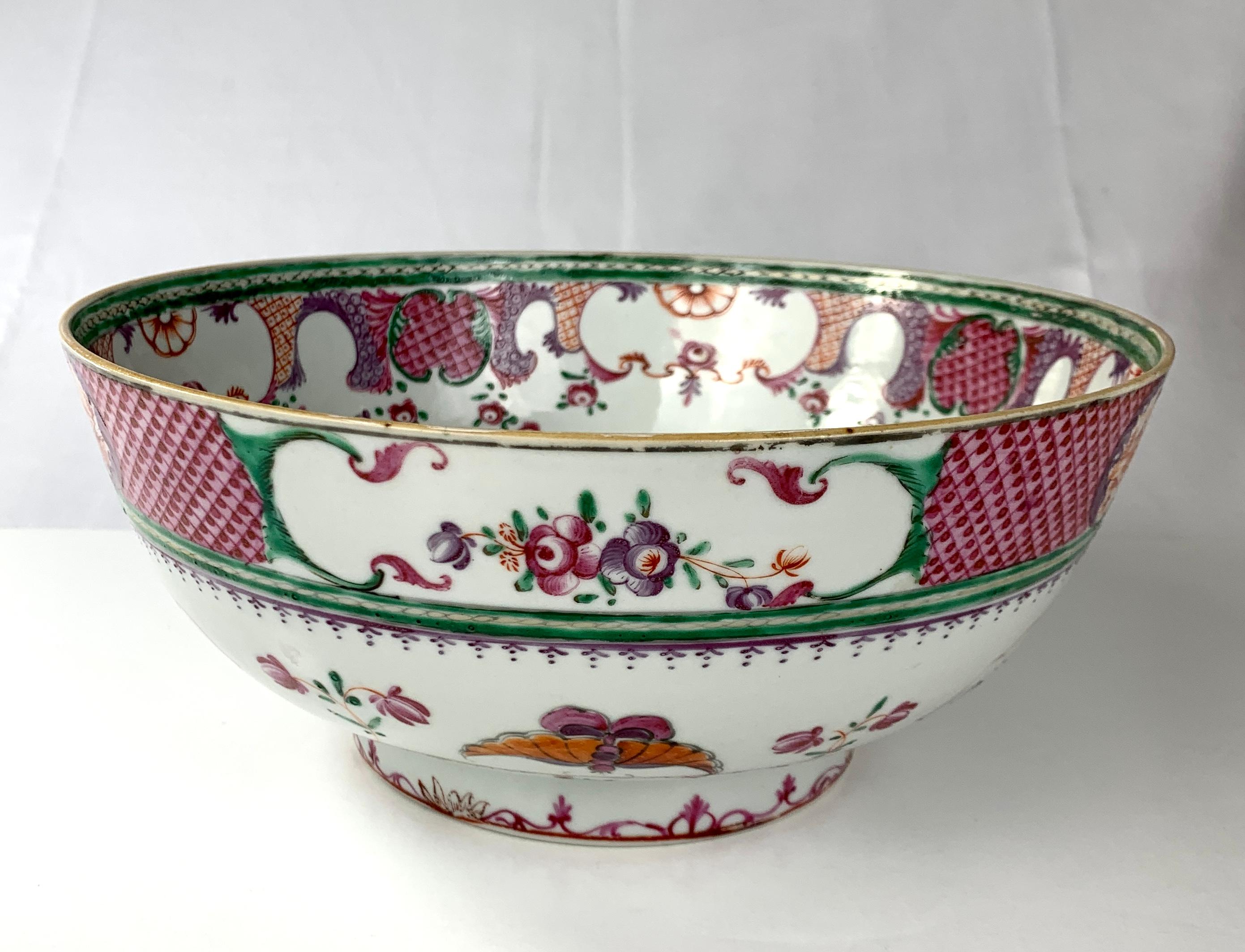 This lovely Chinese porcelain bowl was hand-painted in Famille Rose shades of deep purple, orange, and green.
The outside of this beautiful bowl features a top band of purple diamond patterns inset with panels of blooming peonies and small