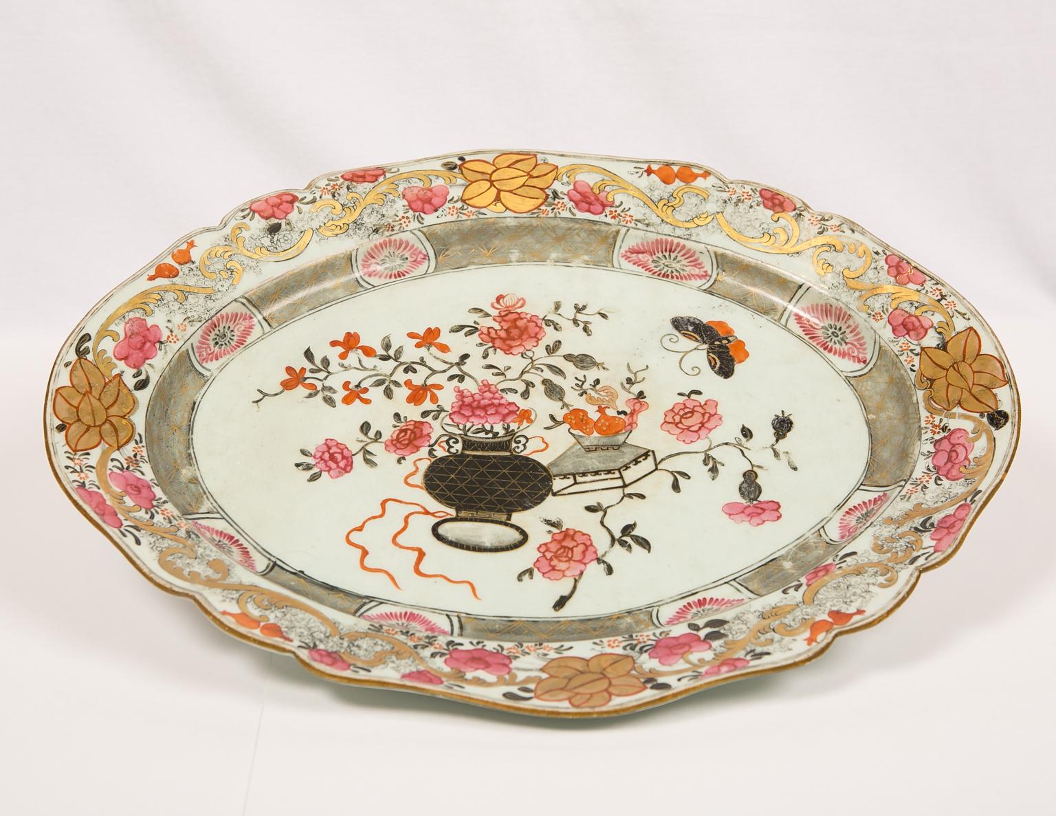 We are pleased to offer this large Chinese porcelain platter which is decorated with vibrant floral patterns in a beautiful palette of pink, gray, black and gold. Made in the first half of the 19th century, it is painted in the center showing a