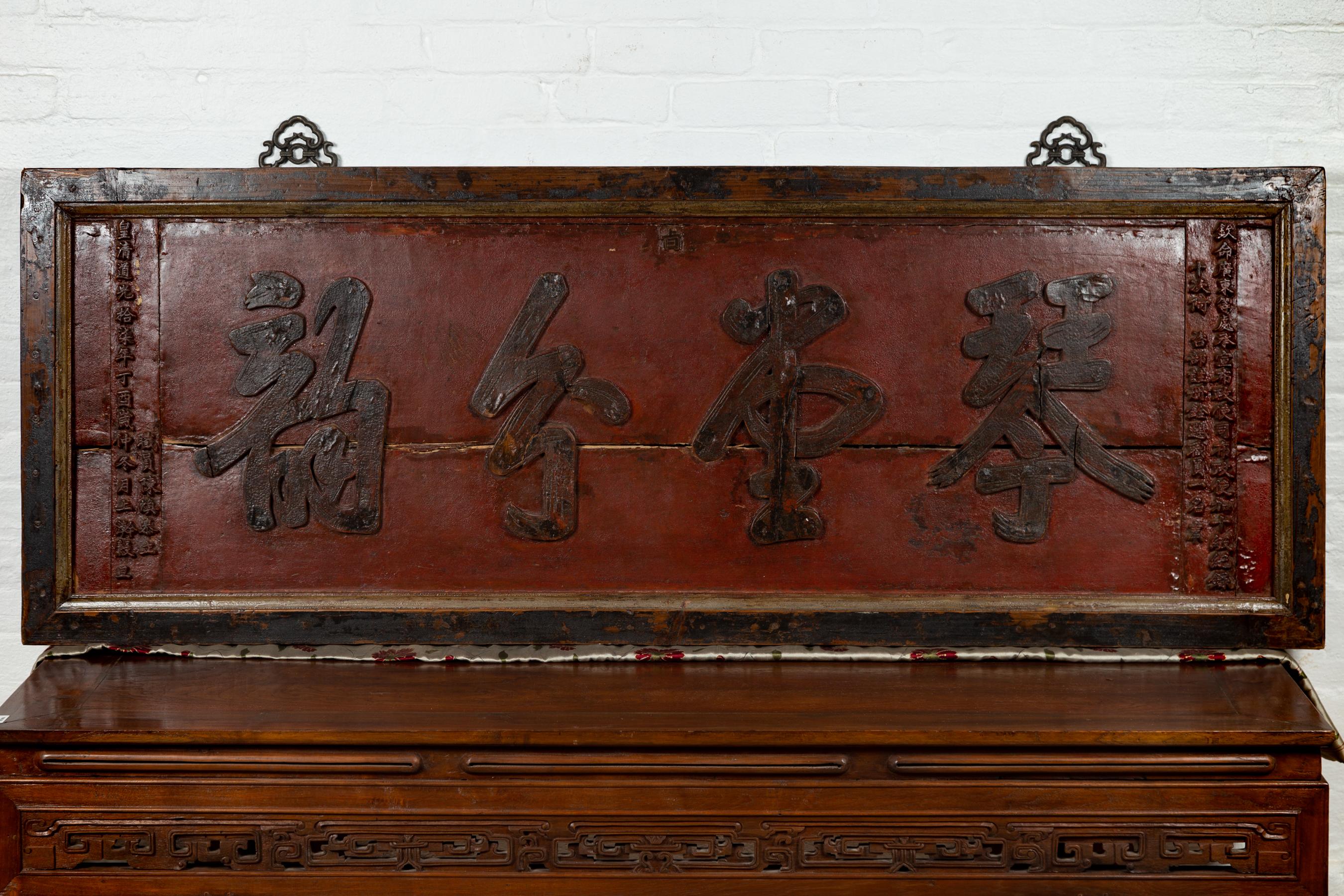 A Chinese antique red lacquered shop sign from the early 20th century, with black calligraphy. Attracting our eyes with its large proportions and red lacquered ground, this large horizontal shop sign will make for a great wall decor. Placed above a