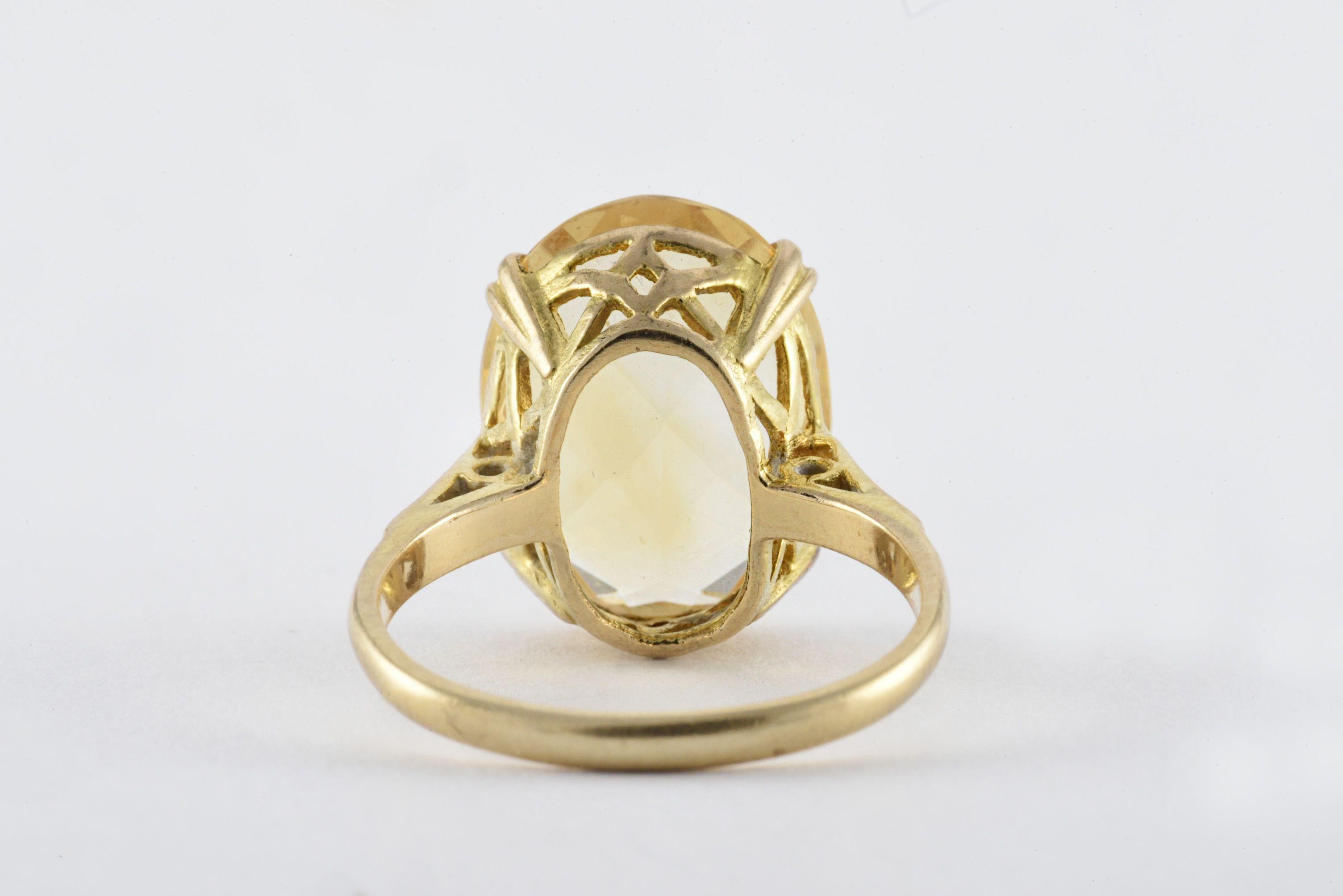 This bold cocktail ring features a large oval-shaped natural yellow citrine measuring 12 x 15 mm set in a 9kt yellow gold openwork gallery. The ring is stamped W&G, 9, 375, anchor, R, and R/ST. It appears the ring was manufactured by Wyatt & Gill,