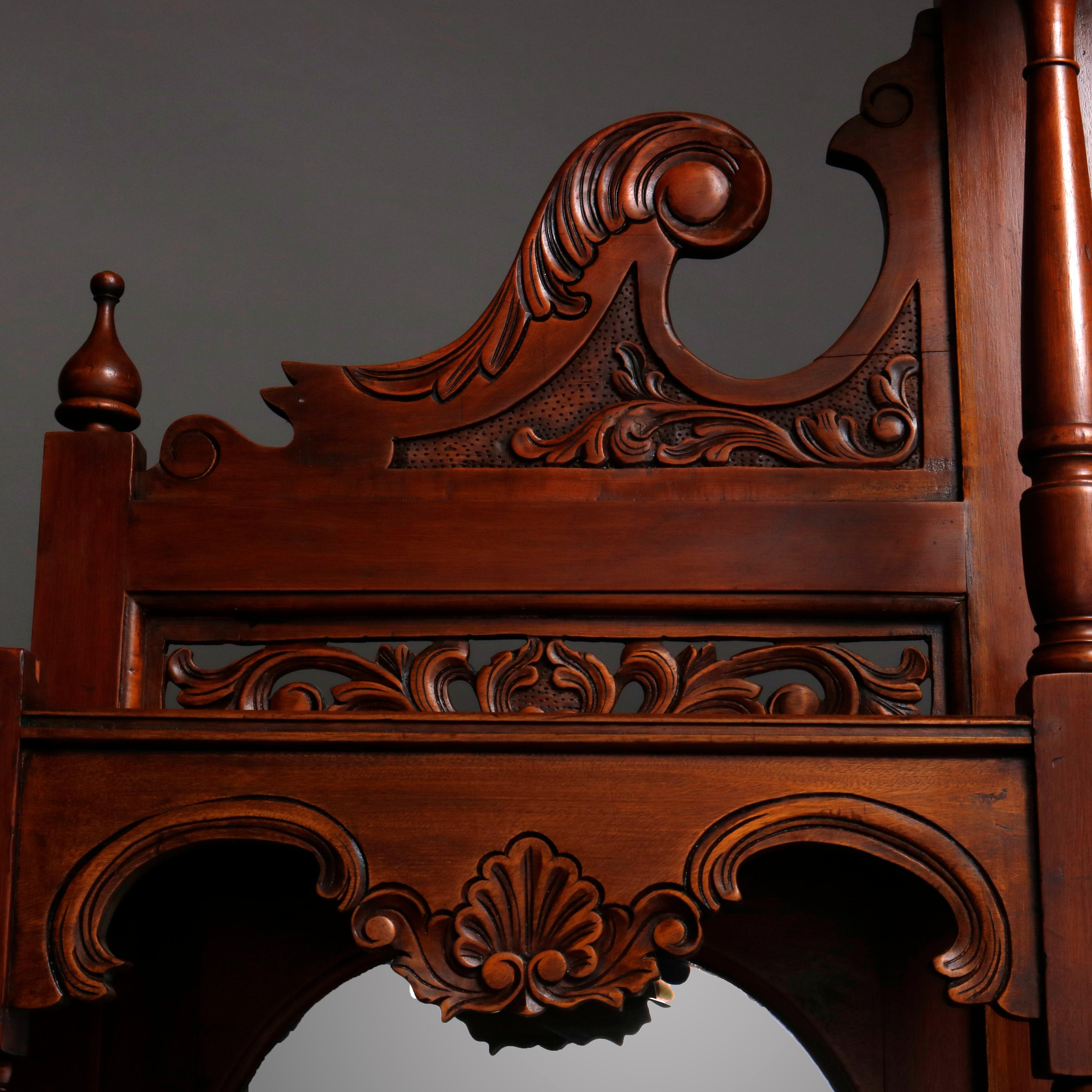 An oversized antique continental sideboard offers carved walnut construction with foliate carved broken arch crest surmounting triple (triptych) upper having three arched and beveled mirrors flanked by turned columns over lower cabinet with three