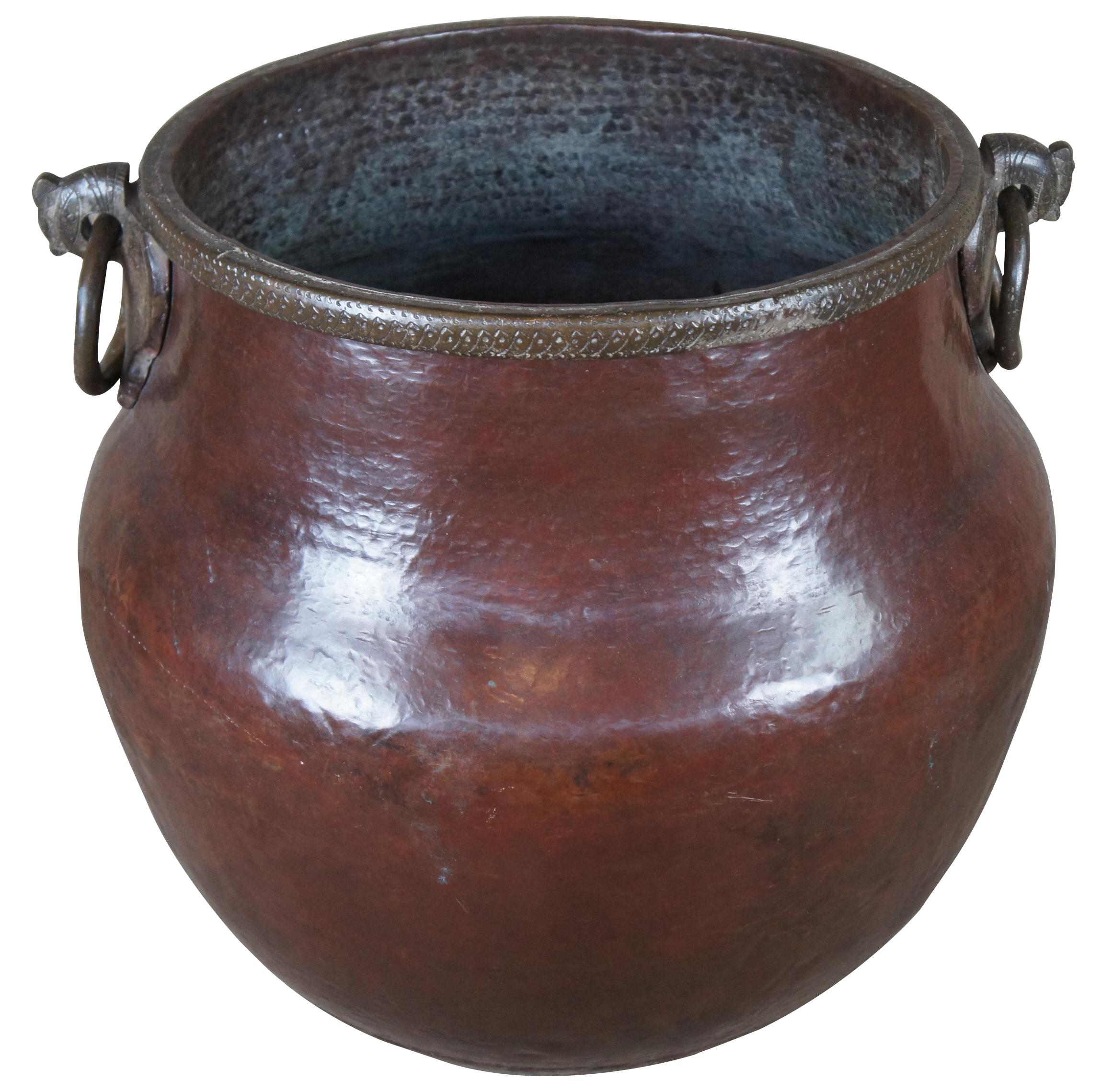 A very large antique hammered copper southern Indian temple water vessel from Tanjore with iron ring handles cock s head mounts and rim band incised and stamped with embellishments.
       