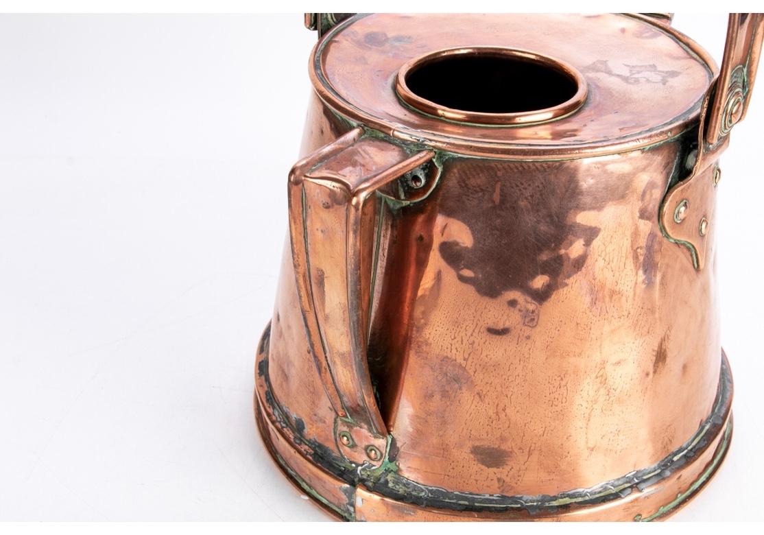 A large and very decorative watering can dating to the industrial era. Tin lined. With both a side handle and large top swivel handle with decorative attachments on the sides. The open center on top lacking a lid. 
Measures: Height with handle 15