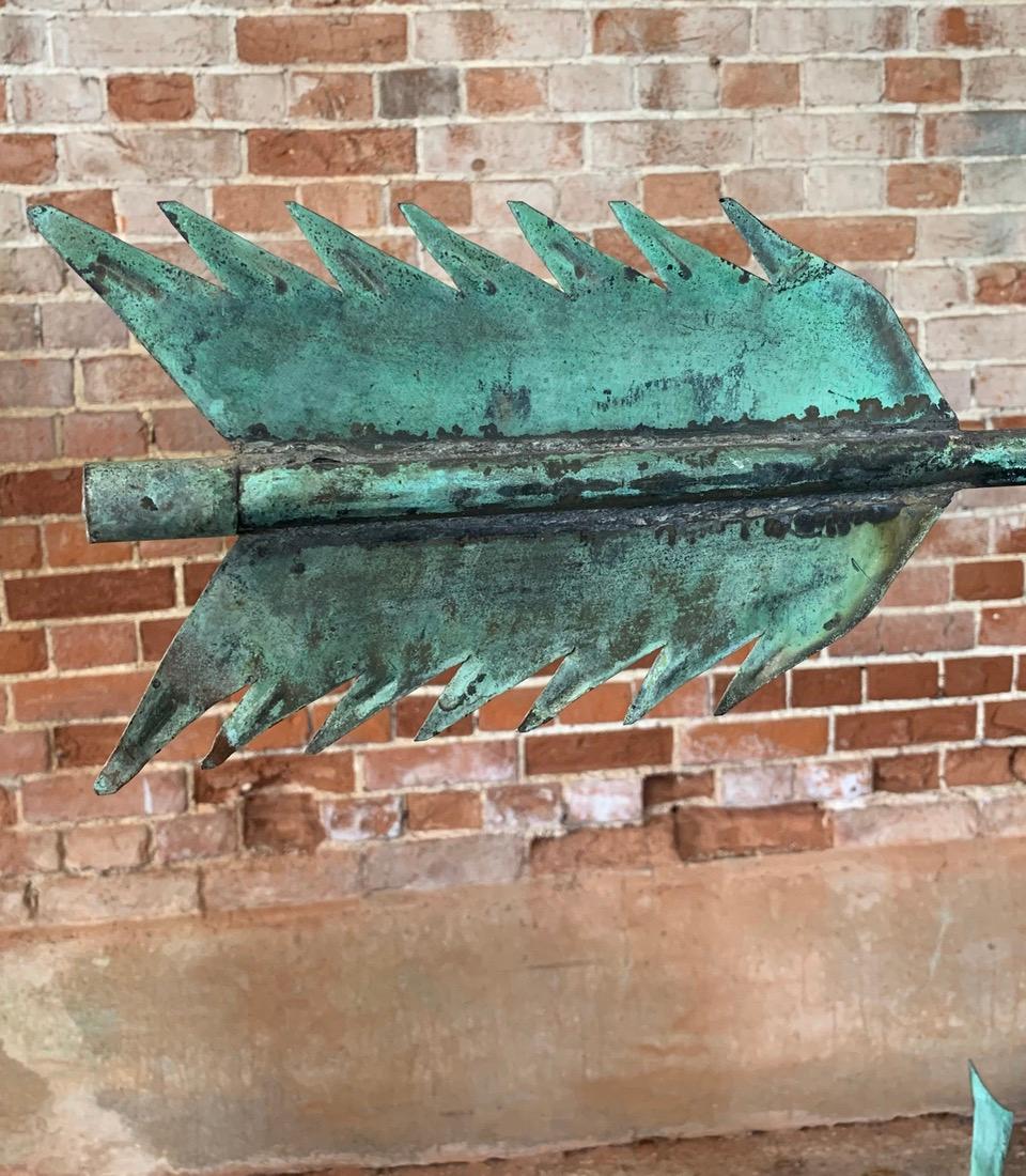 A large early 20th century copper directional arrow weathervane which has a beautiful natural verdigris. Circa 1910. 
It has been mounted on a later metal base for display purposes. It can be unbolted from the base and used again as a working