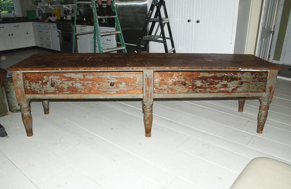 An ideal center piece for a kitchen or shop as it has two large drawers with pulls. Aged patina, much of the paint has worn off in the front of the table. A fantastic piece that would add warmth and tone to any modern, rustic or industrial interior.