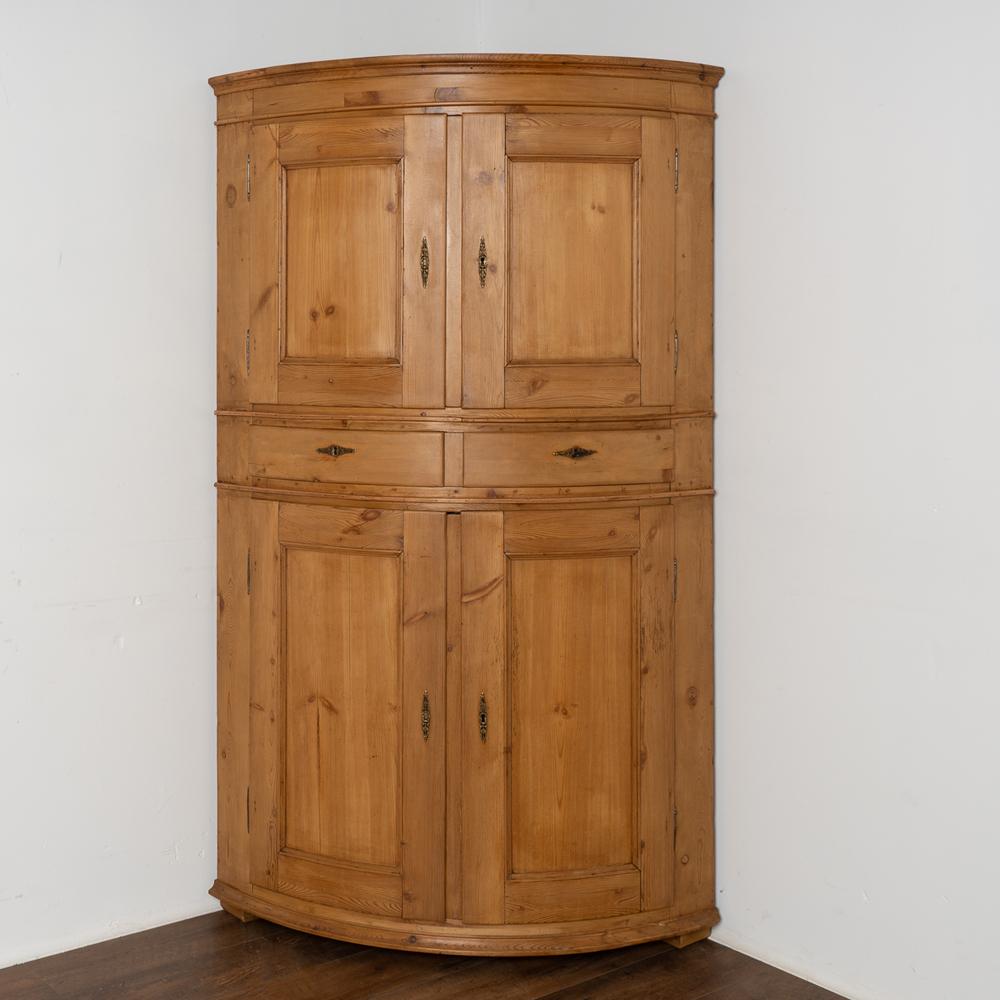 The lovely appeal of this large bow front corner cabinet is due to the elegant Danish styling and soft patina of the aged pine.
The cabinet is made in two sections, both crafted with large curved paneled doors.
Behind the doors are a series of