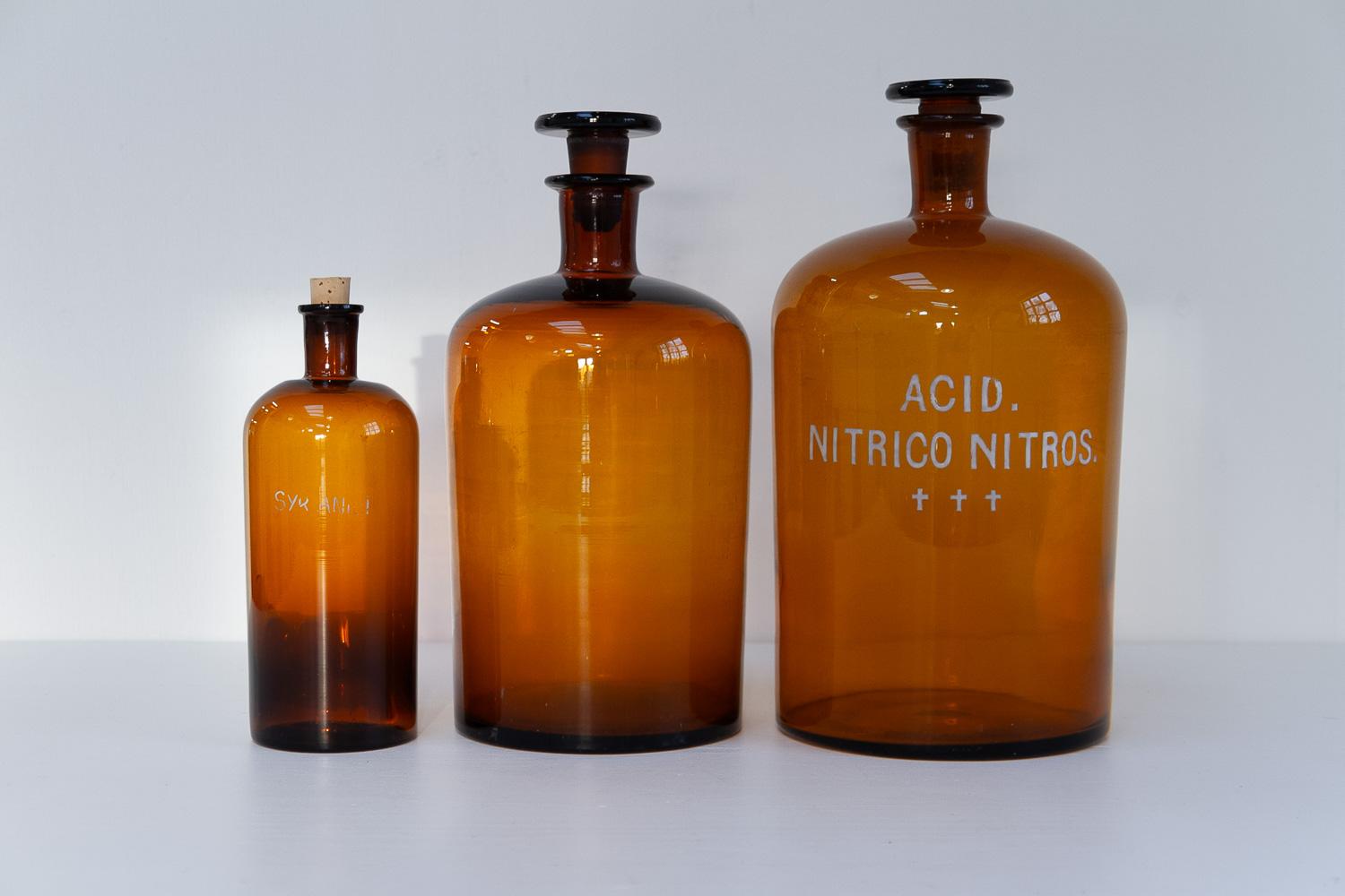 Large Antique Danish Pharmacy Glass Bottles, 1900s. Set of 3.

Set of three large hand blown apothecary bottles in brown/golden amber glass with stoppers.

Bottle sizes: 
Extra large: Diameter 18 cm, height  36 cm
Large: Diameter 16 cm height 34