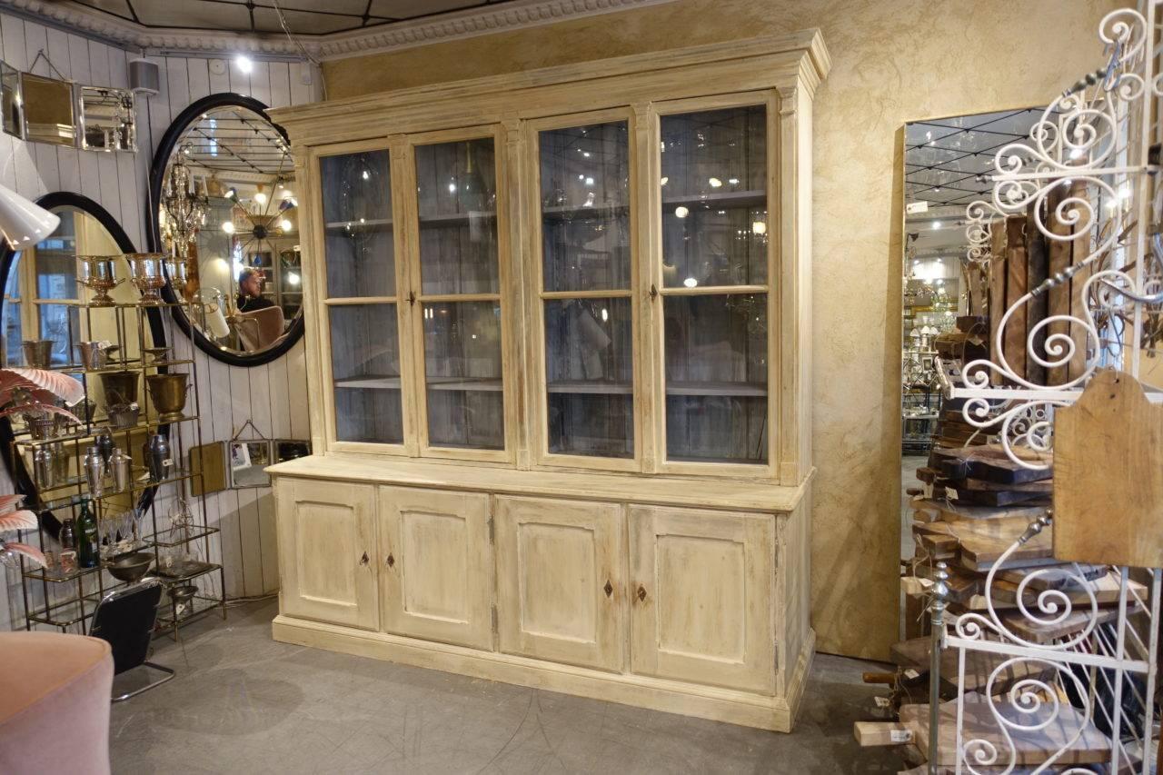 Handsome and huge rarely seen antique French two-part book cabinet. Four beautiful cabinet doors, with their original glass. The wooden shelves can be height adjusted. The under part has practial drawers to the right, and shelving to the left. All