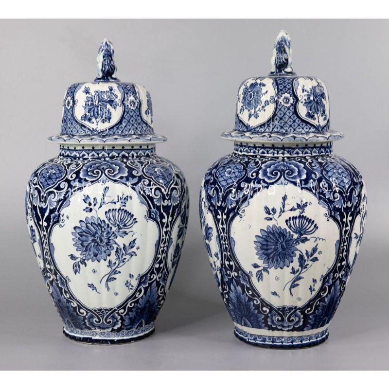 A lovely set of two early 20th-Century Dutch Delft faience lidded ginger jars by well known Dutch maker, Maastricht. Maker's marks on the reverse. These stunning vases are a nice large size with a wonderful ribbed shape, blue and white floral motif,