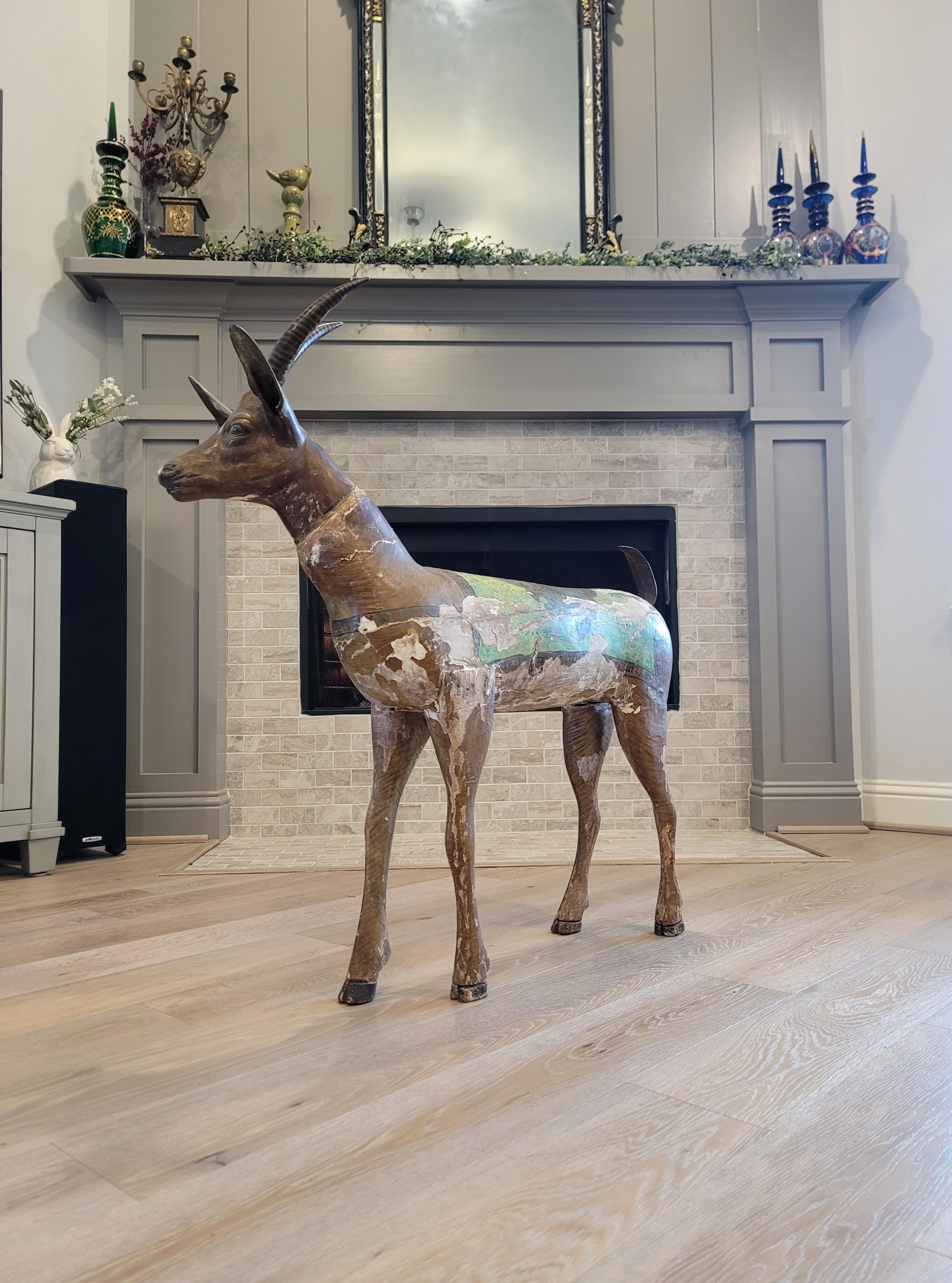 A large, rare, and most impressive antique hand carved and painted wood and metal stylized antelope African folk art sculpture with beautifully aged distressed patina. 

Handmade in East Africa, dating to around the late 19th / early 20th century,