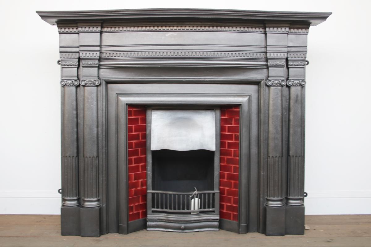 Large antique Edwardian cast iron fireplace surround, each leg with twin engaged columns flanking a bow fronted frieze with dentil moulding below a bow fronted shelf. Dated 1905.

Finished in traditional black grate polish giving a gunmetal sheen.